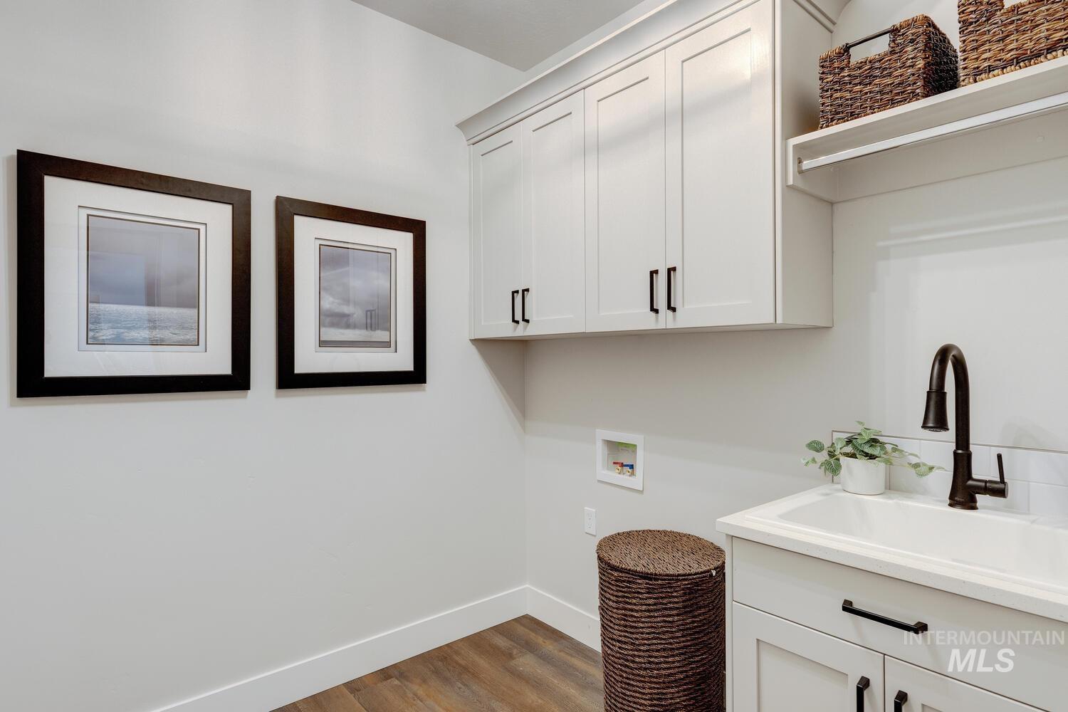 Laundry area featuring cabinet space, washer hookup, and wood finished floors