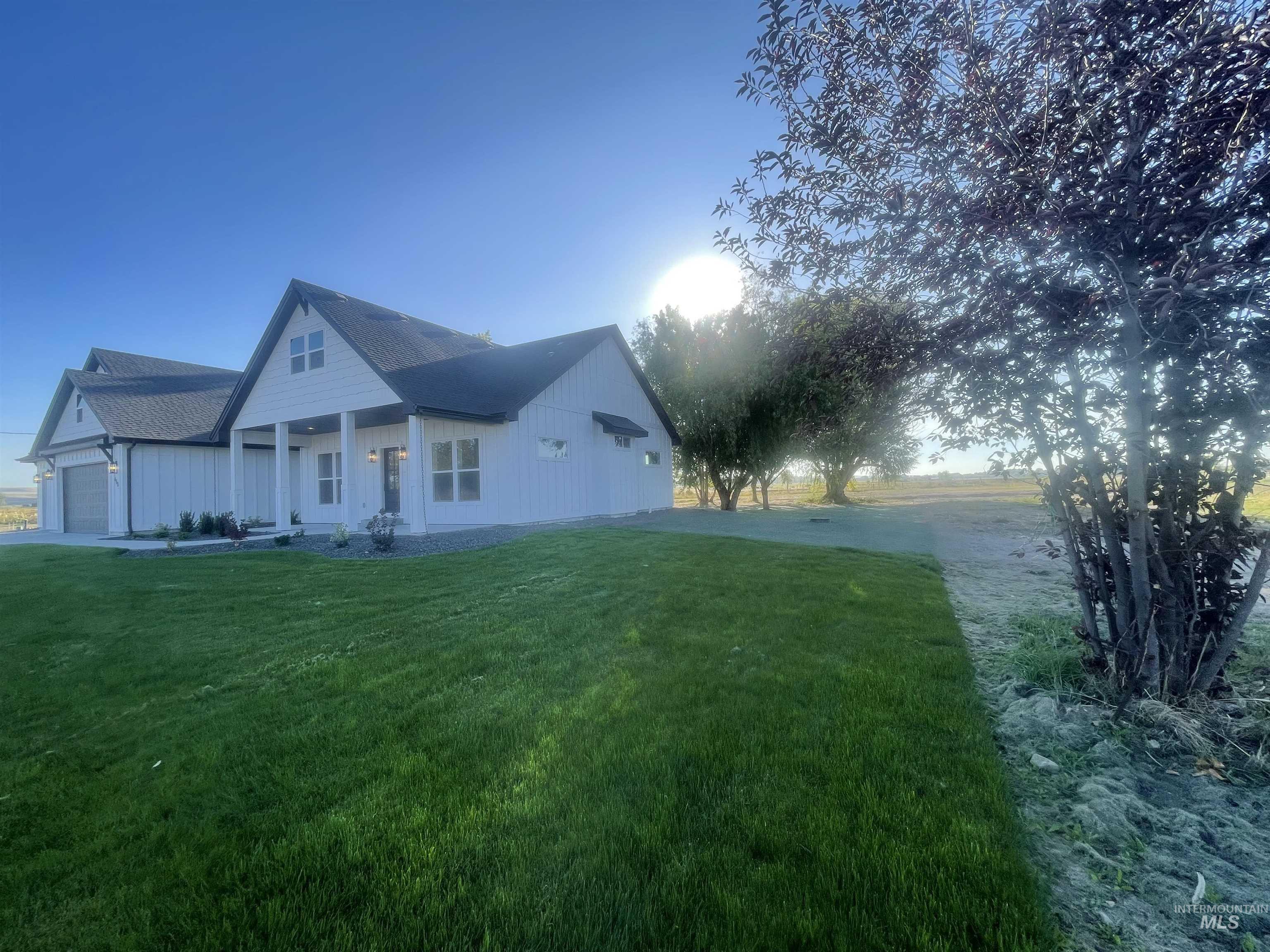 View of side of property with a porch, a yard, a garage, and roof with shingles