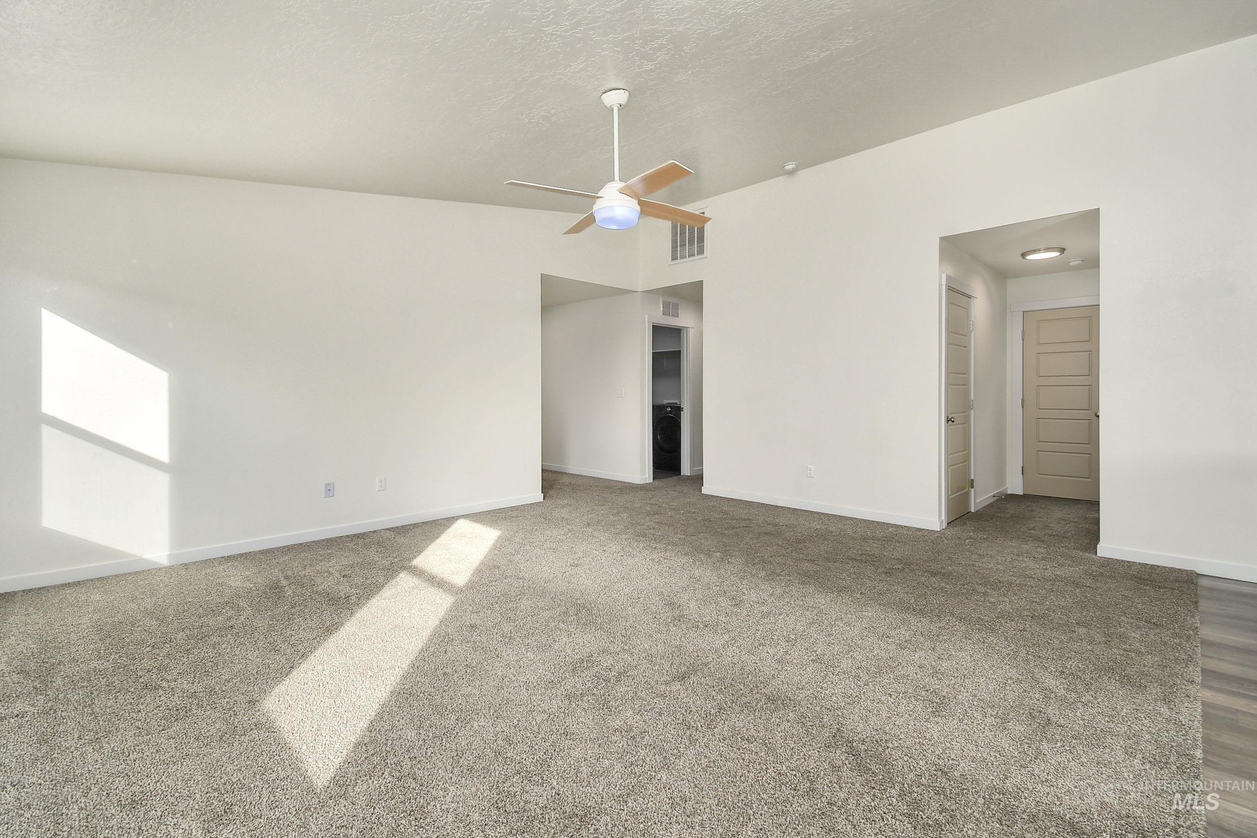 Carpeted empty room featuring ceiling fan and a textured ceiling