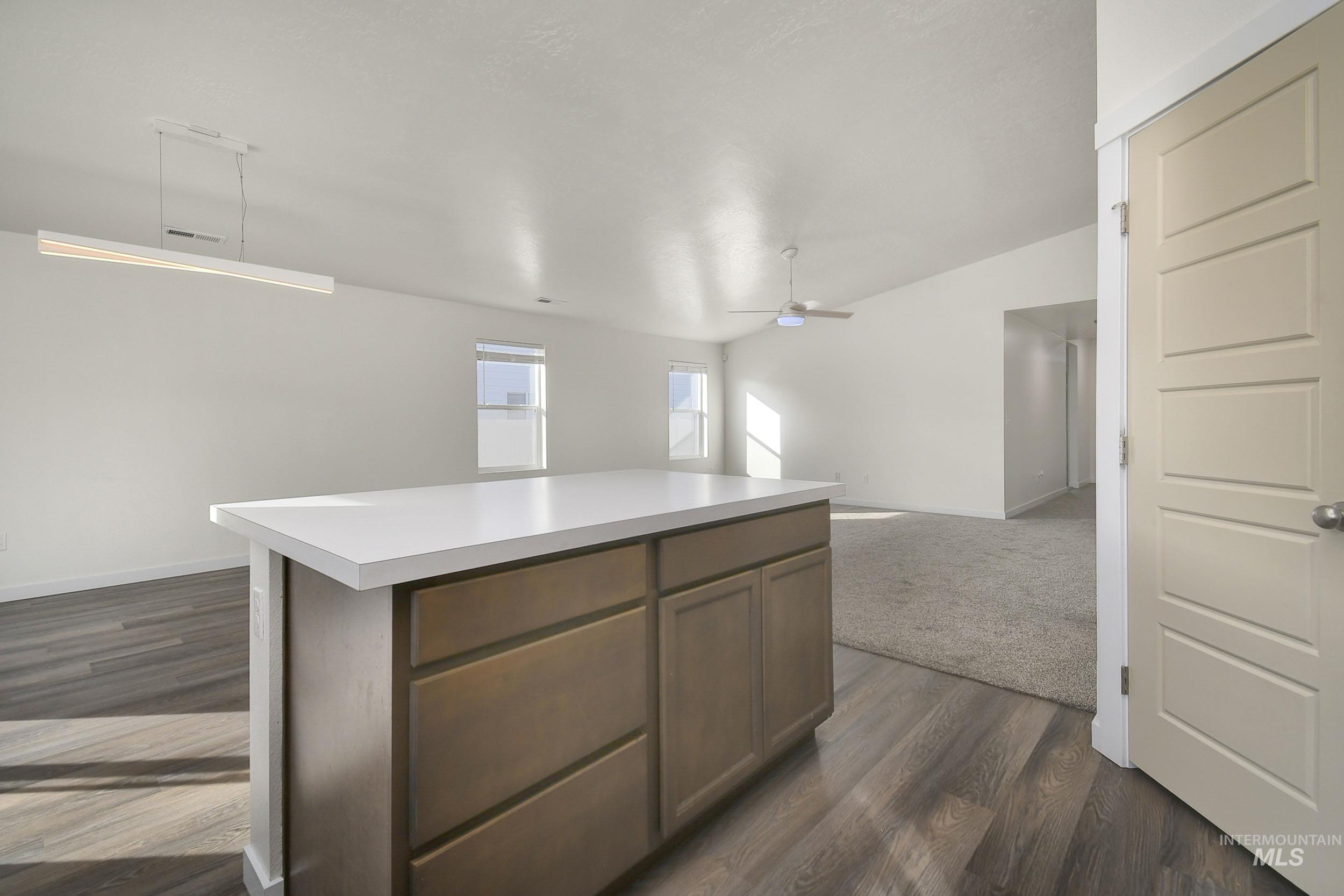 Kitchen with light countertops, open floor plan, a ceiling fan, and a kitchen island