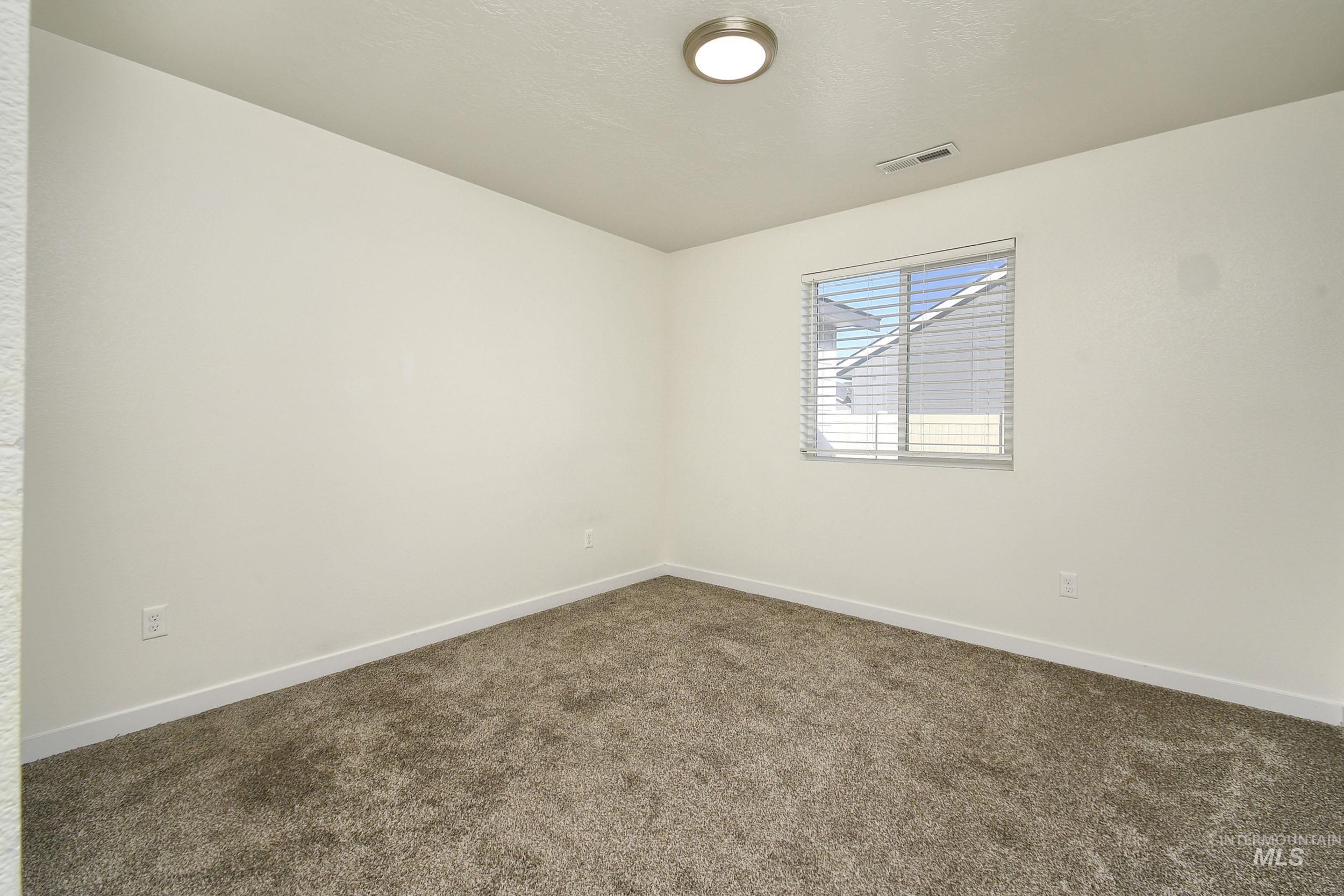 Empty room featuring dark carpet and a textured ceiling