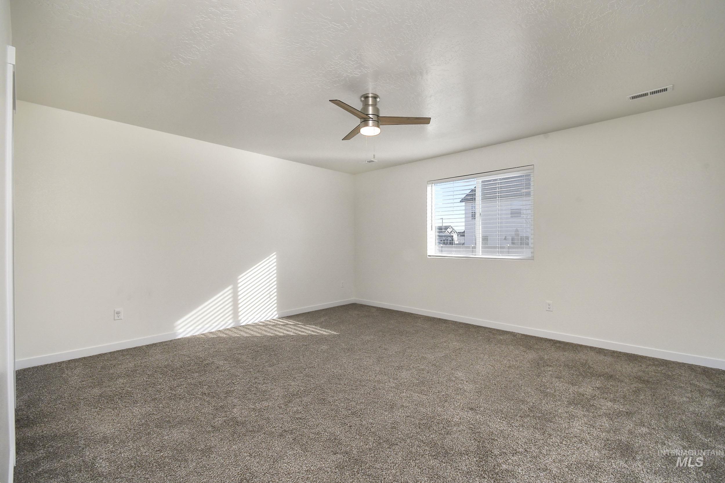 Spare room with carpet, a textured ceiling, and ceiling fan