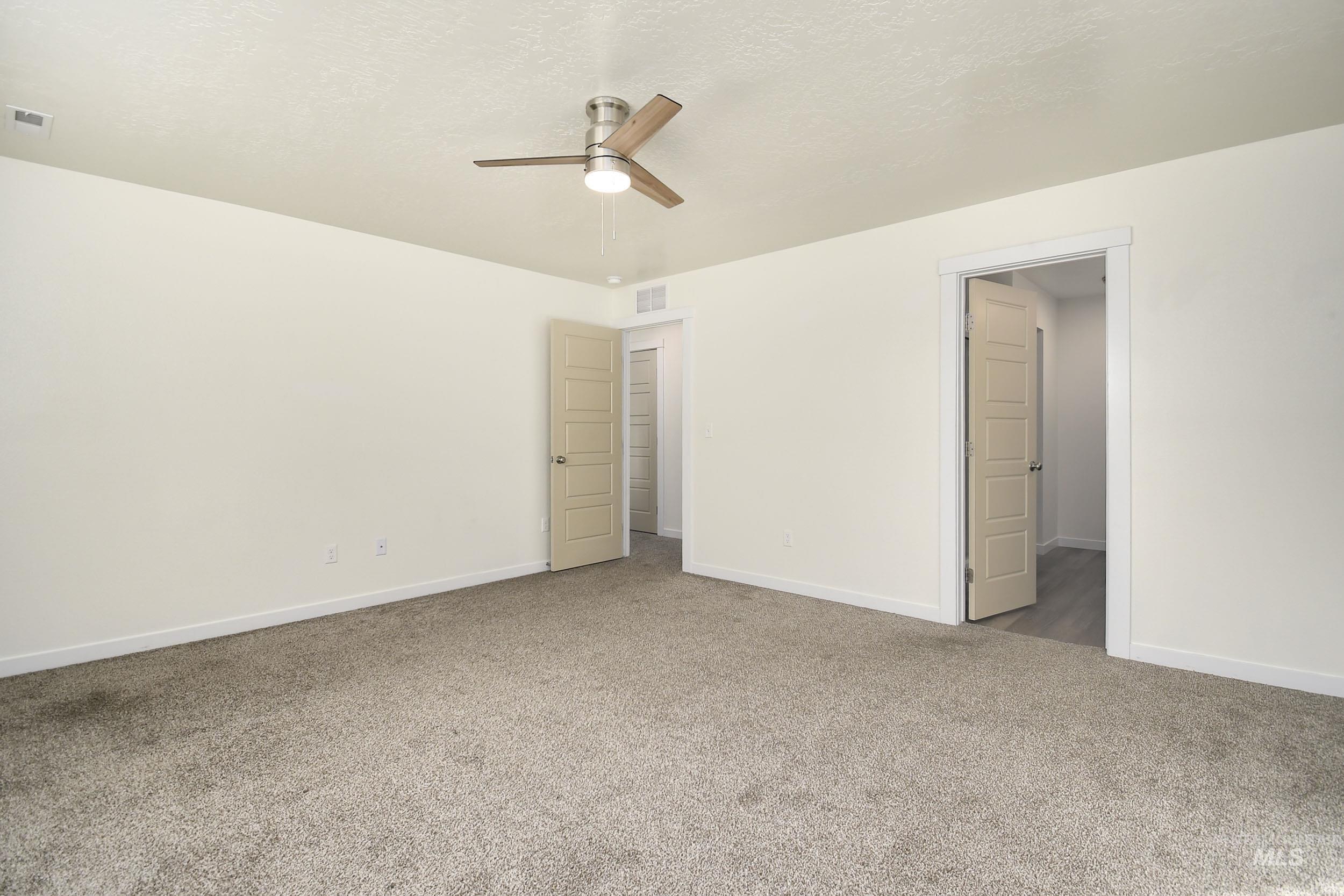 Unfurnished bedroom featuring carpet floors, ceiling fan, and a textured ceiling