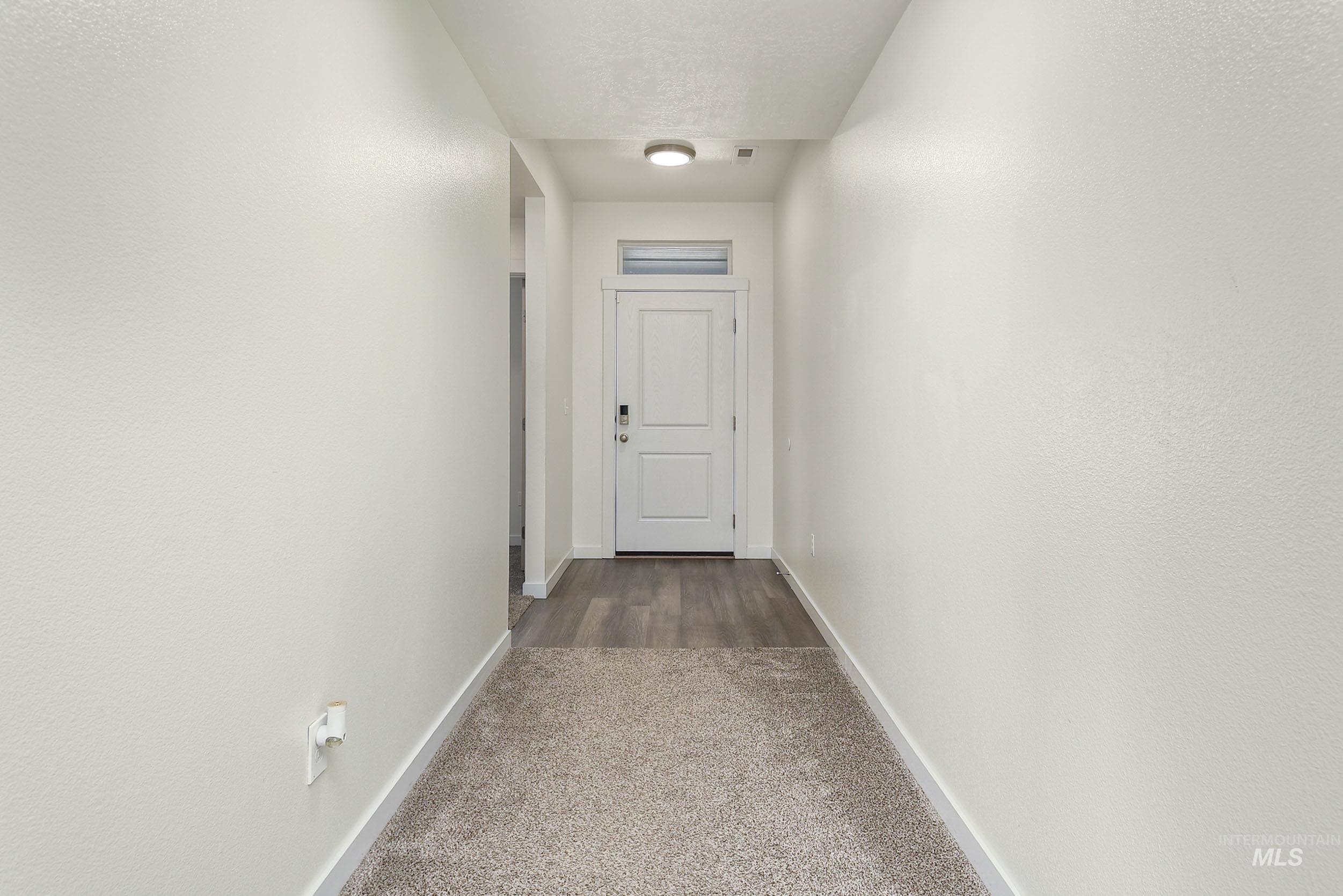 Hallway with dark colored carpet and baseboards