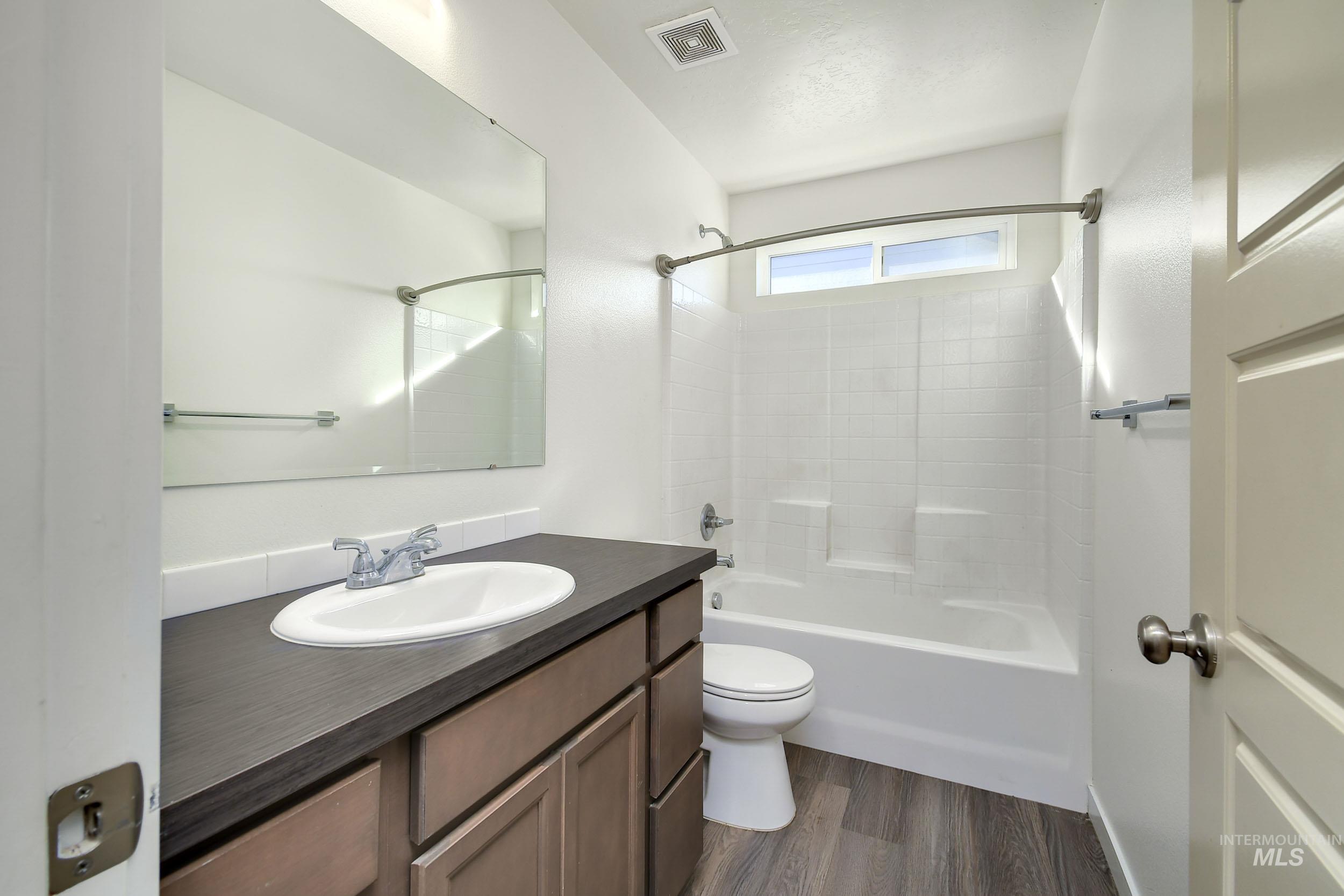Full bathroom featuring vanity, tub / shower combination, and dark wood finished floors