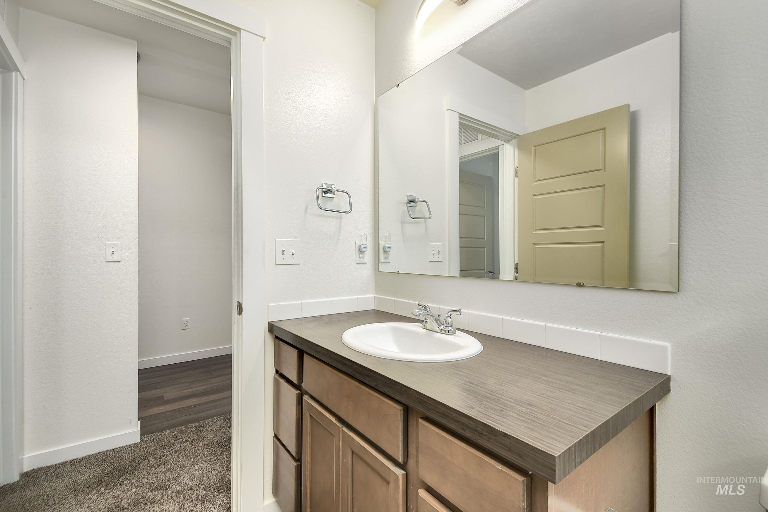 Bathroom with vanity and dark colored carpet