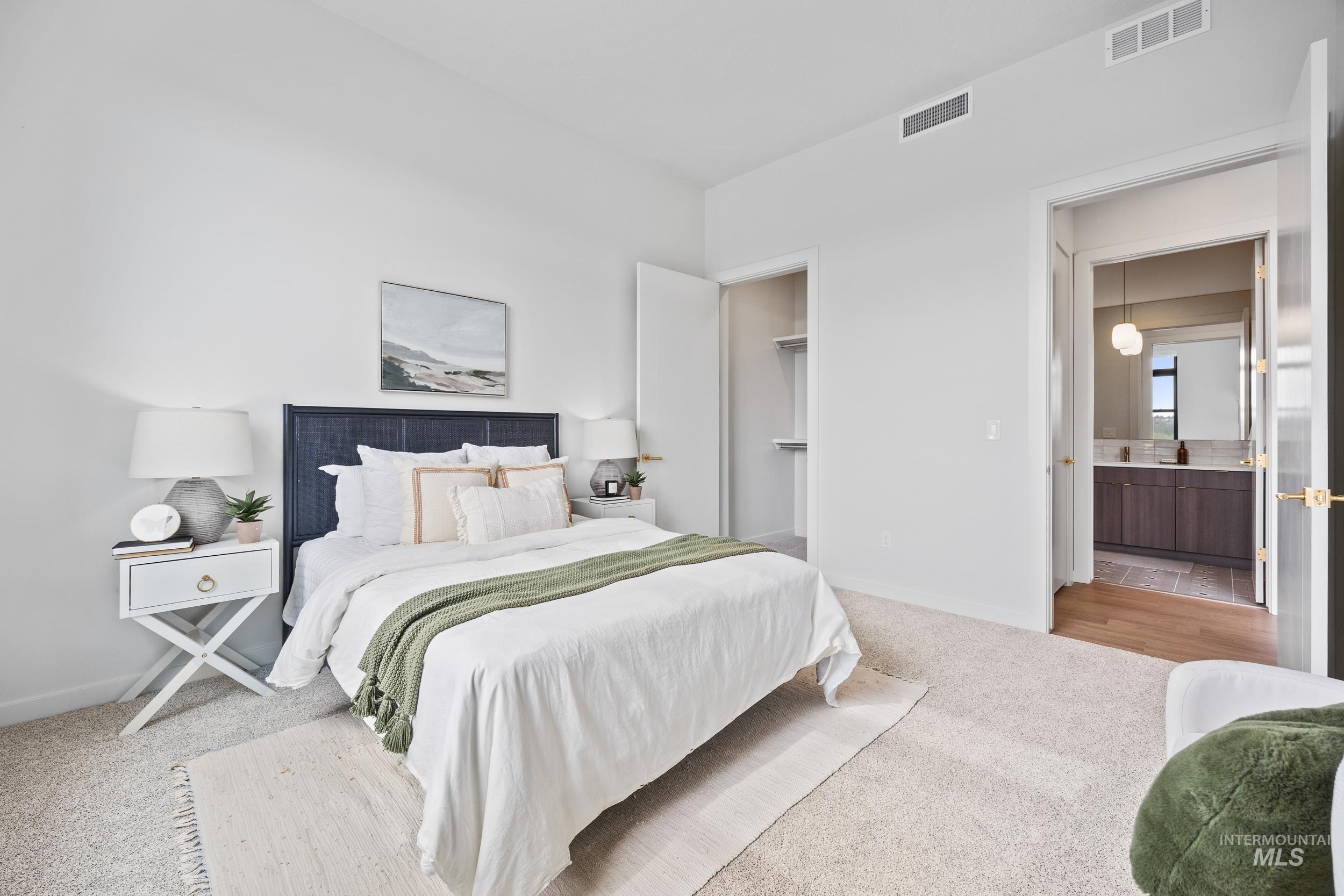 Carpeted bedroom featuring a spacious closet and ensuite bath