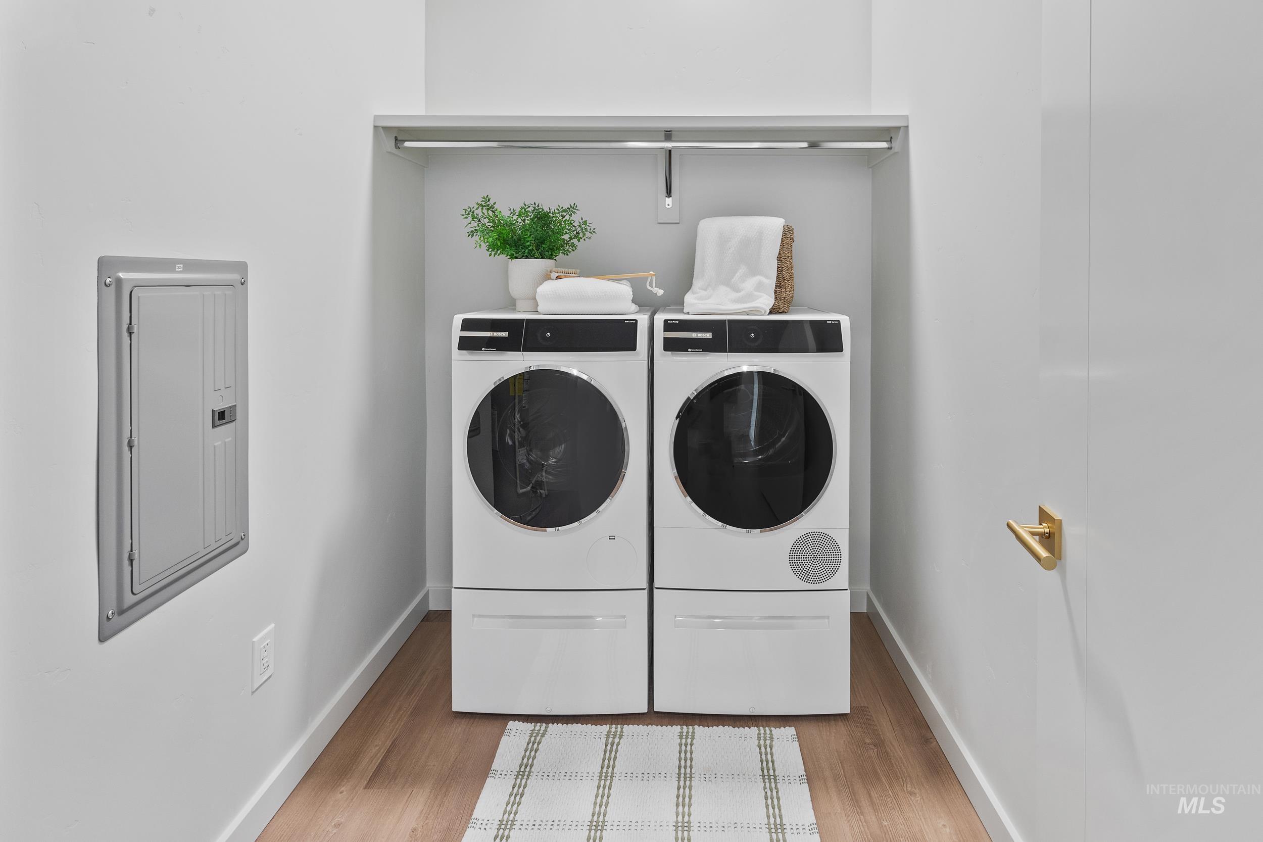 Washroom featuring light wood-type flooring, electric panel, and washer and dryer