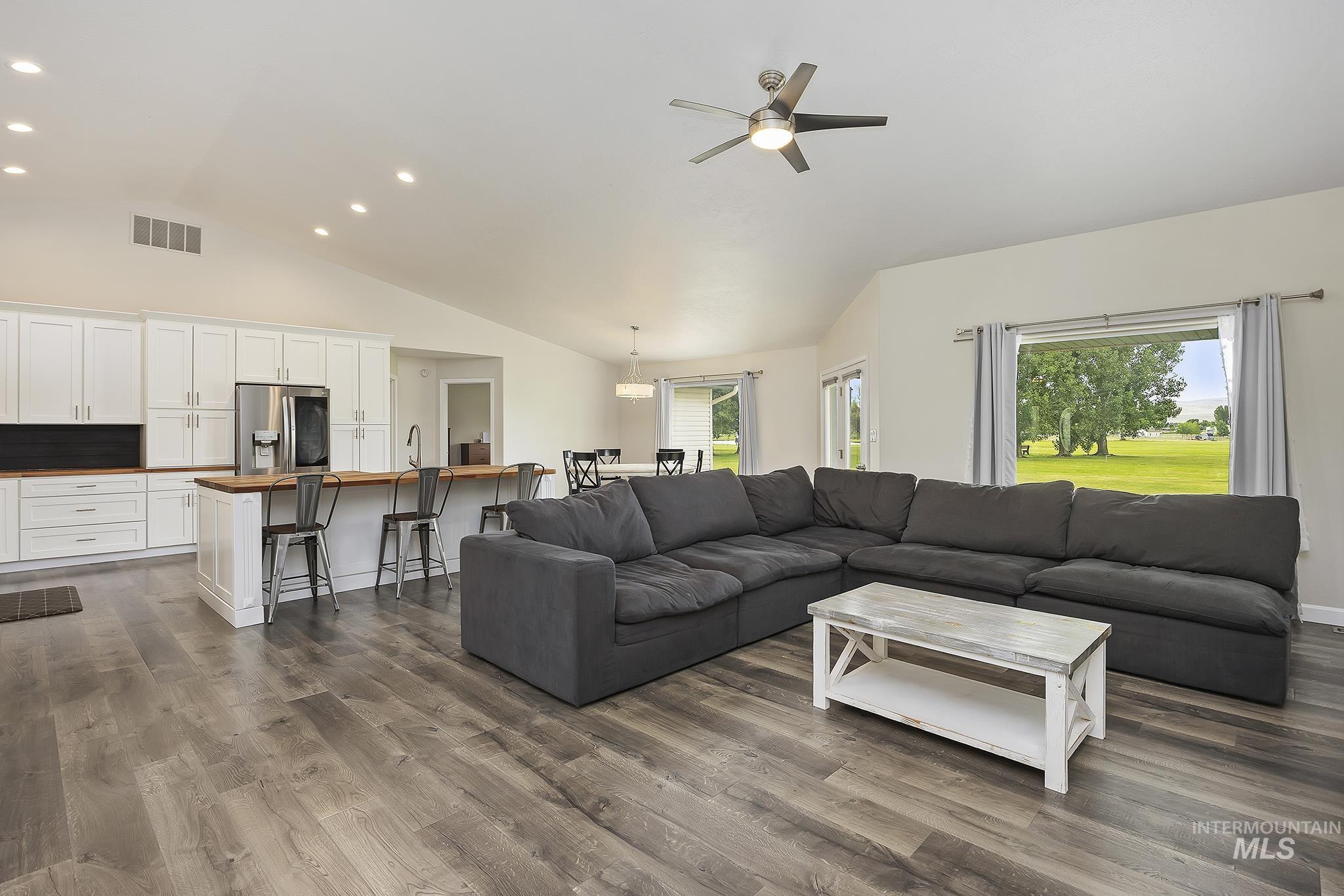 Living room with dark wood-type flooring, recessed lighting, a ceiling fan, and high vaulted ceiling