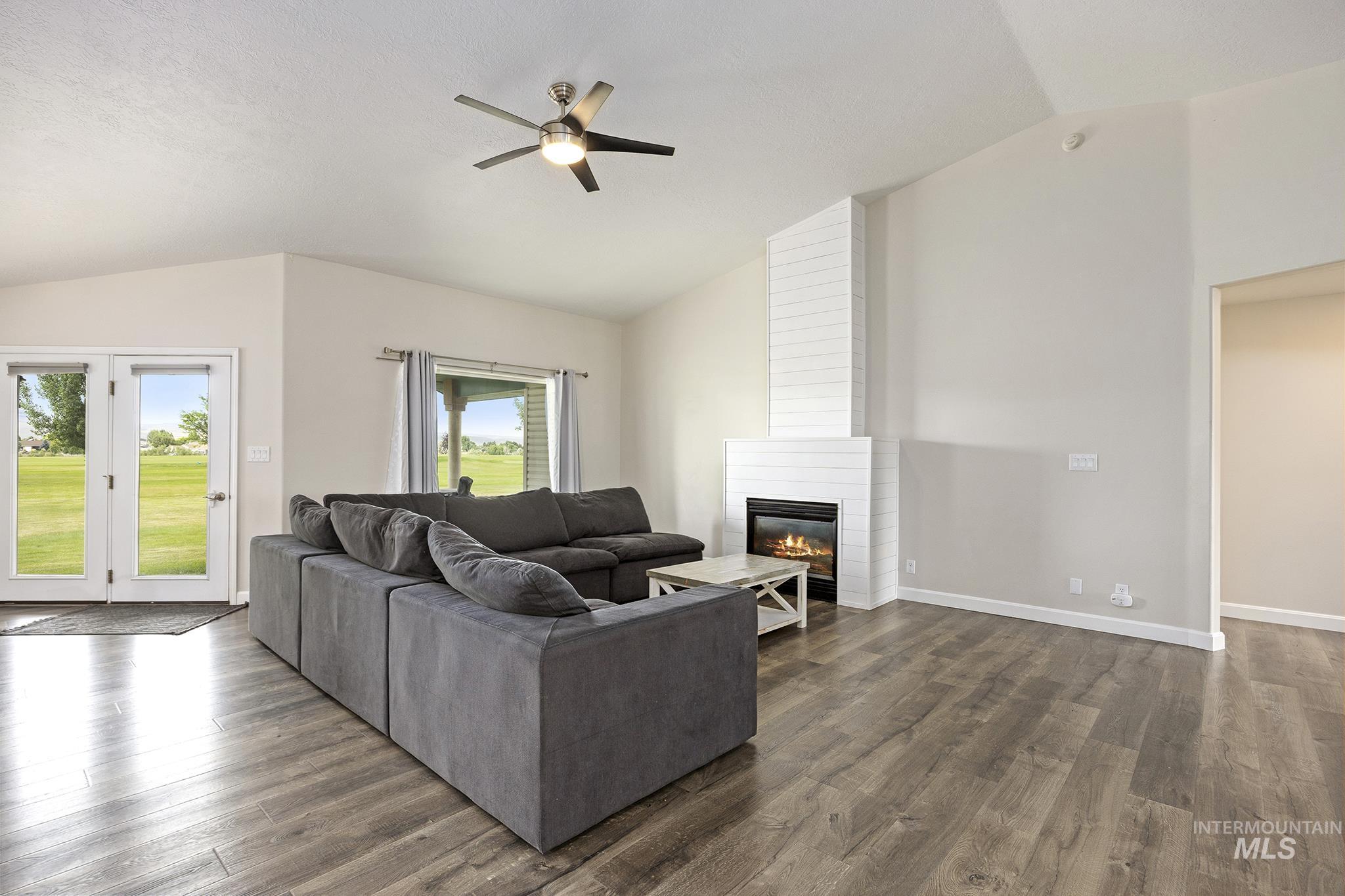 Living area featuring lofted ceiling, dark wood finished floors, a fireplace, and ceiling fan