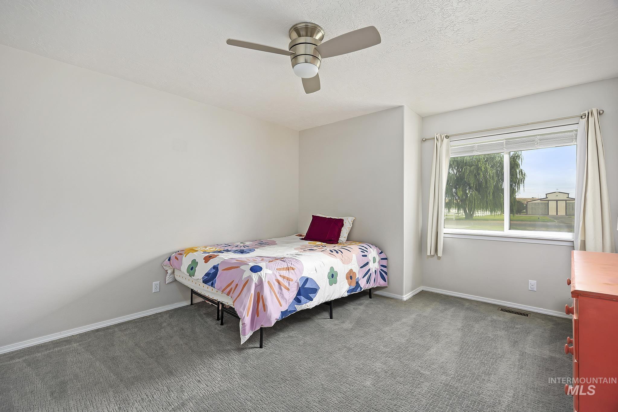 Bedroom with carpet flooring, a ceiling fan, and a textured ceiling