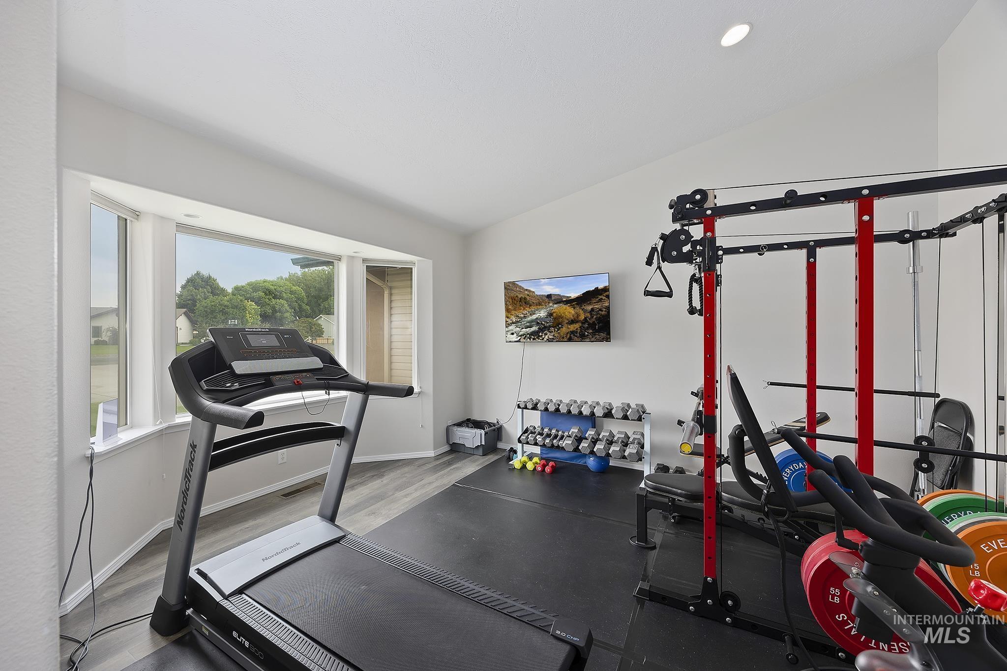 Exercise area with lofted ceiling and wood finished floors