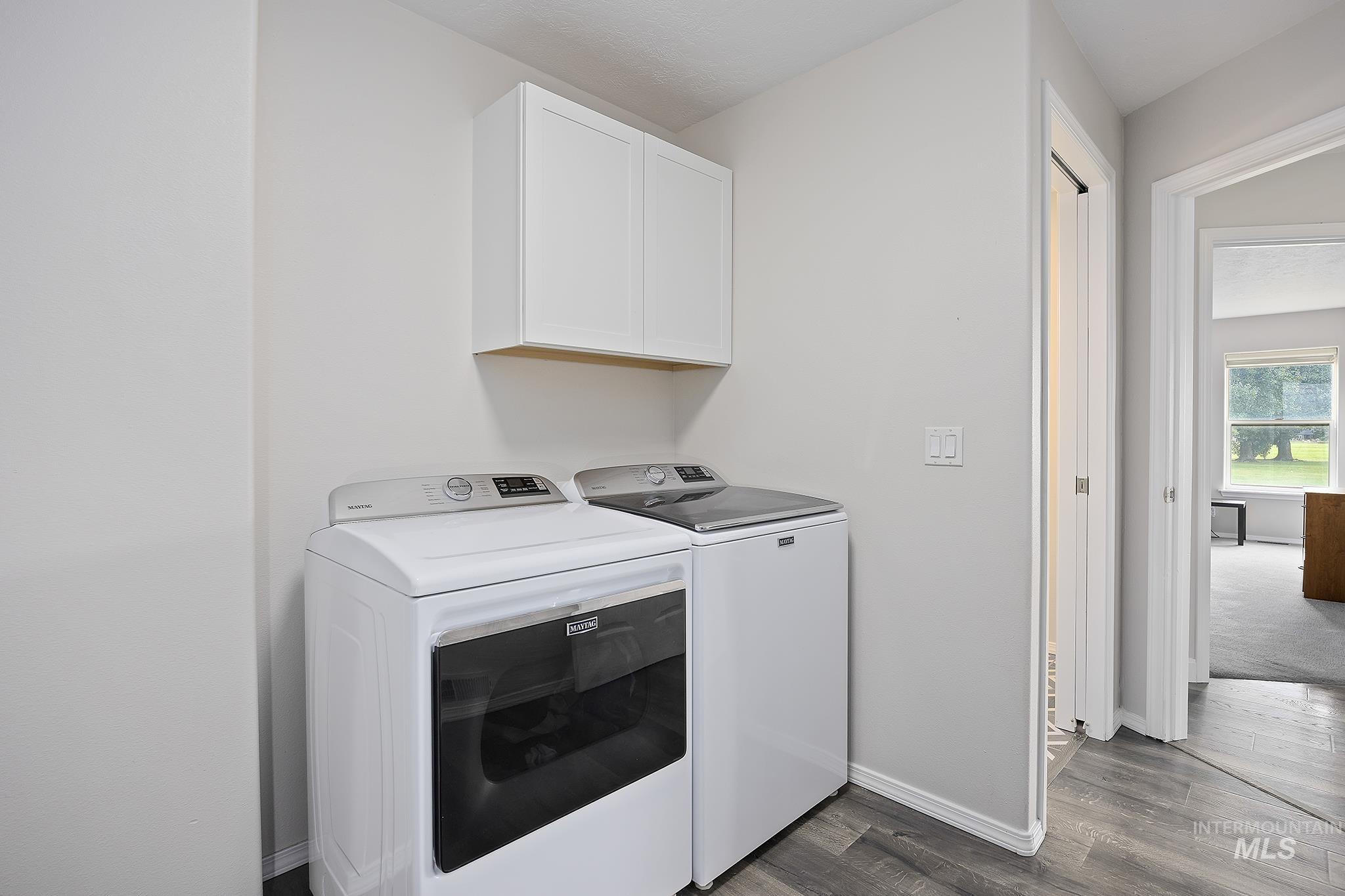 Laundry area featuring cabinet space, dark wood-style flooring, and washer and dryer