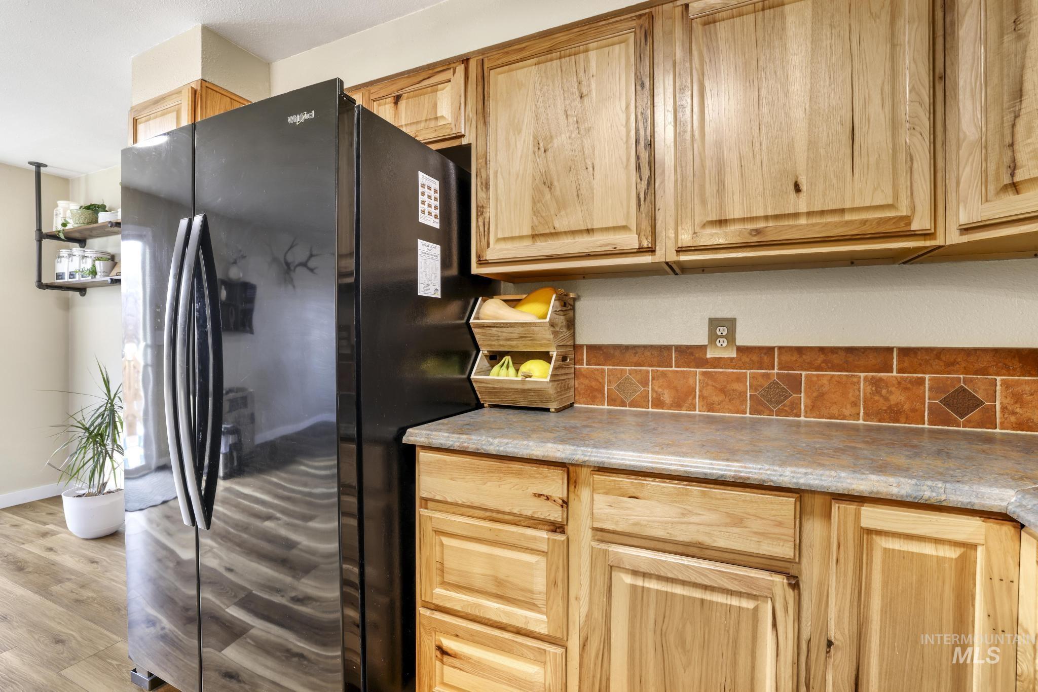 Kitchen featuring freestanding refrigerator, light brown cabinets, light countertops, and light wood finished floors