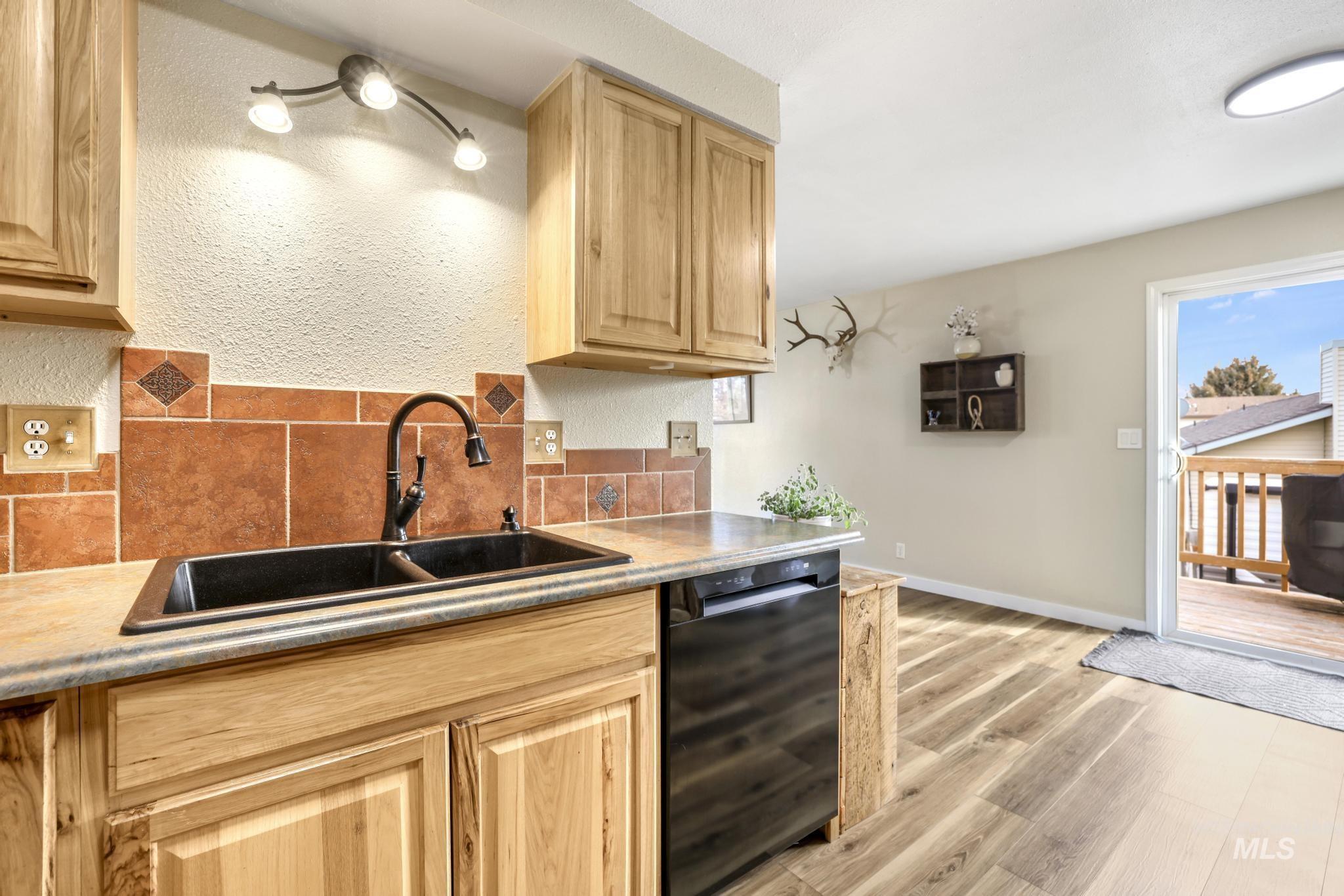Kitchen featuring tasteful backsplash, black dishwasher, light brown cabinets, and light countertops