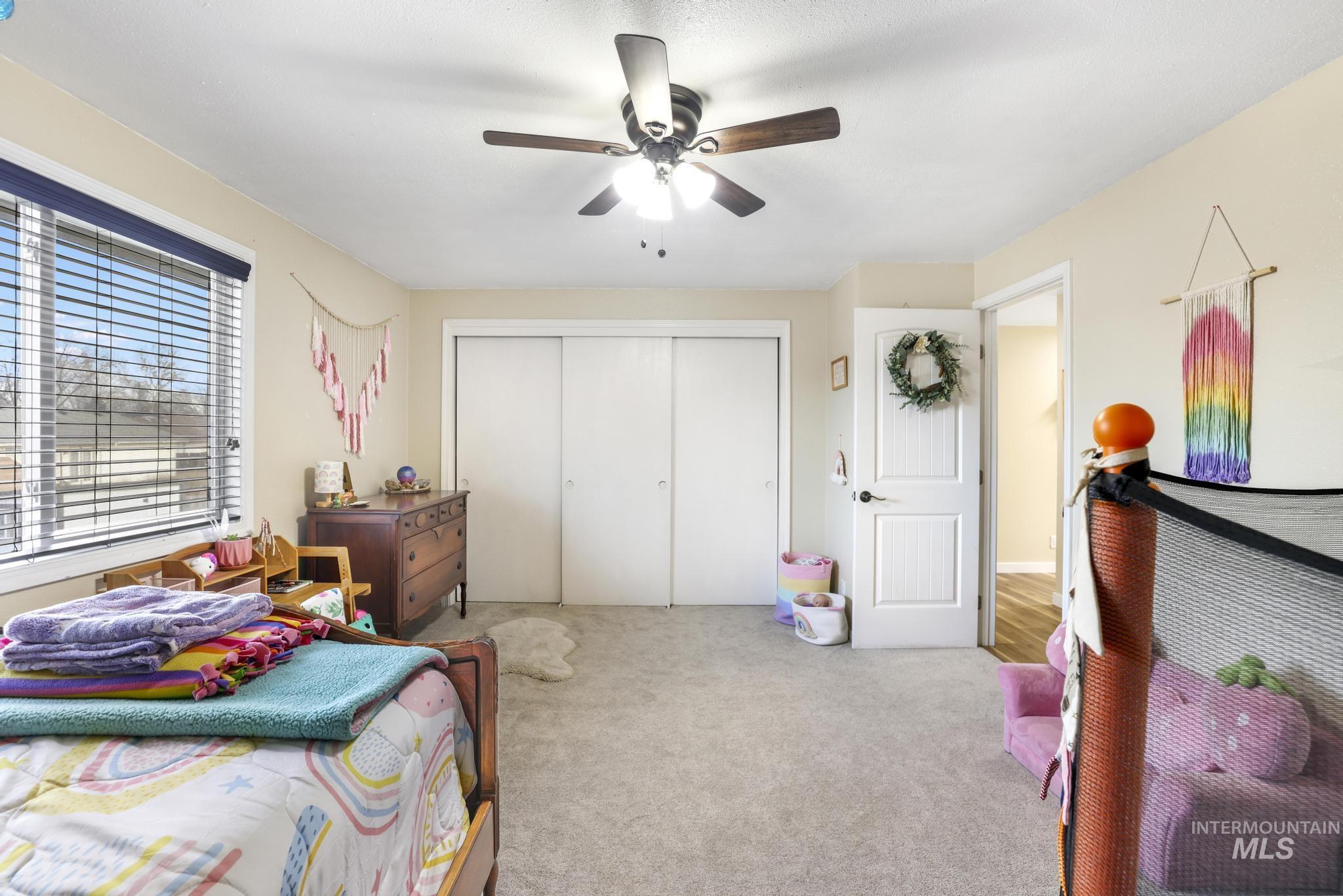 Carpeted bedroom featuring a ceiling fan and a closet