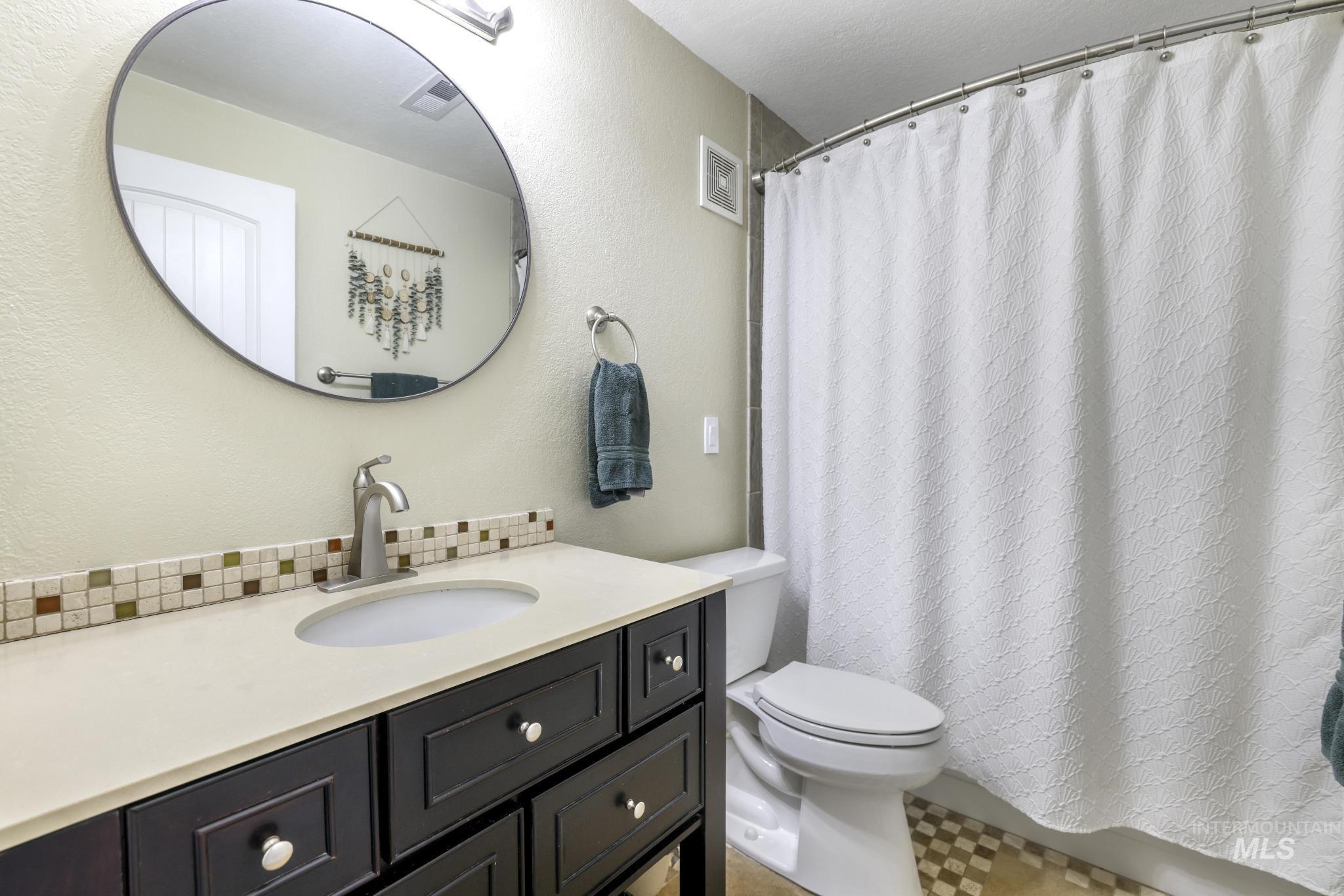 Full bath with vanity, a shower with shower curtain, and a textured wall