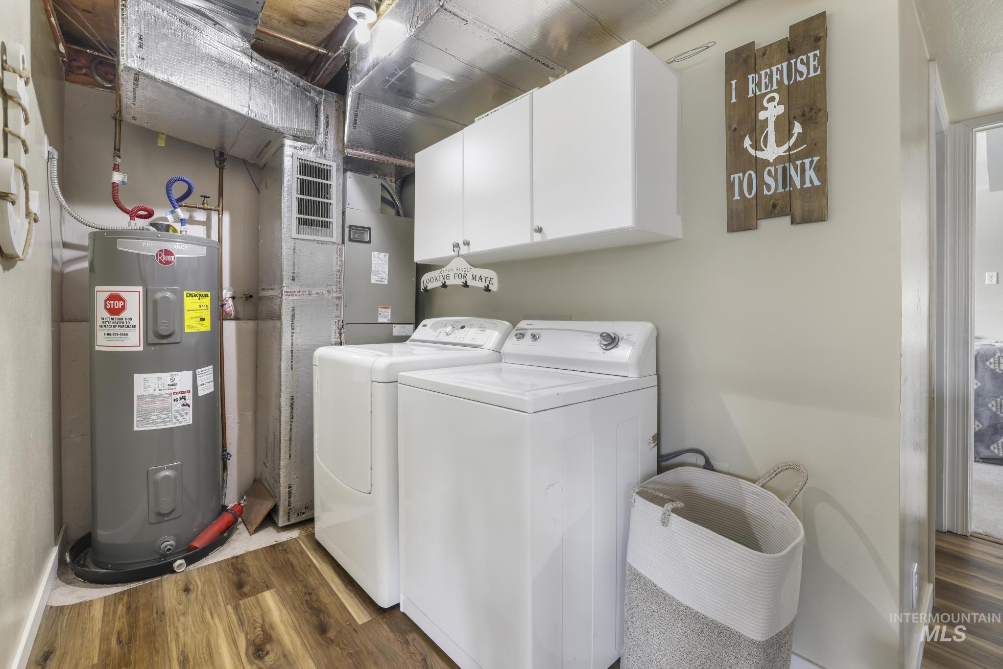 Washroom with water heater, dark wood-style floors, separate washer and dryer, cabinet space, and heating unit