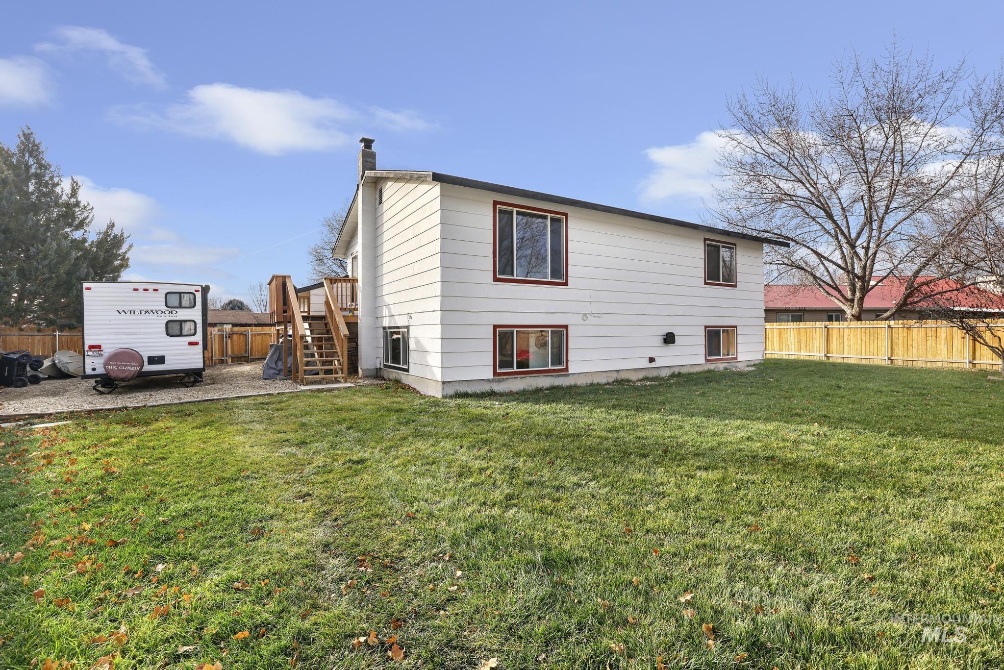 Rear view of house featuring a fenced backyard, a chimney, a deck, and stairs