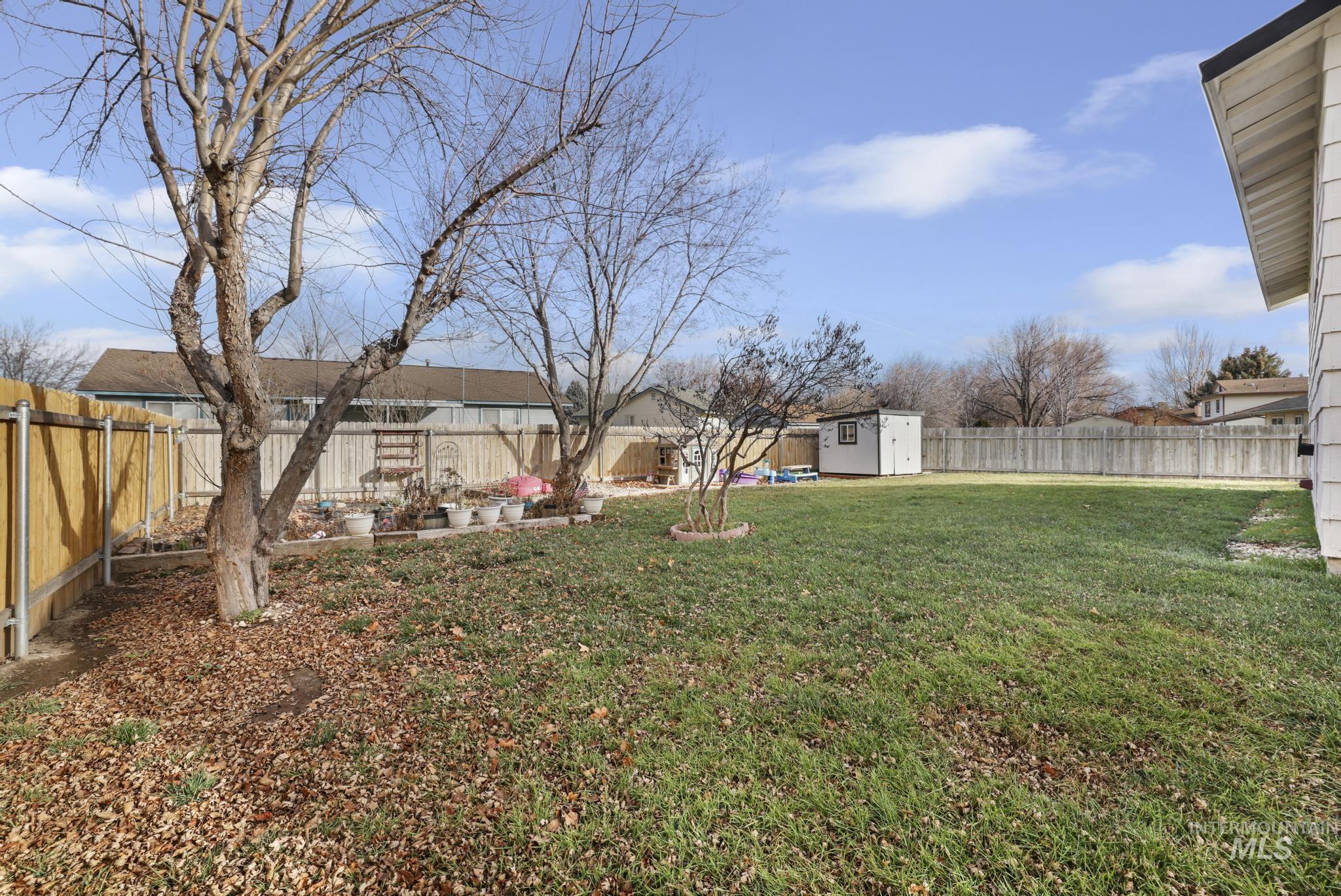 Fenced backyard featuring a shed