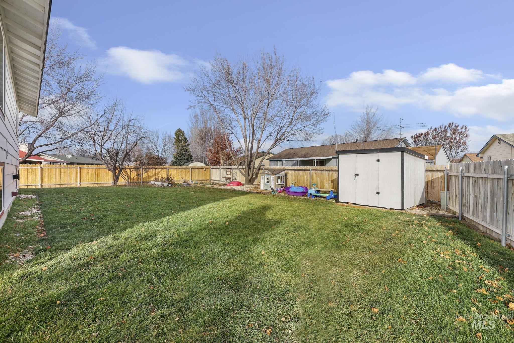 Fenced backyard featuring a shed