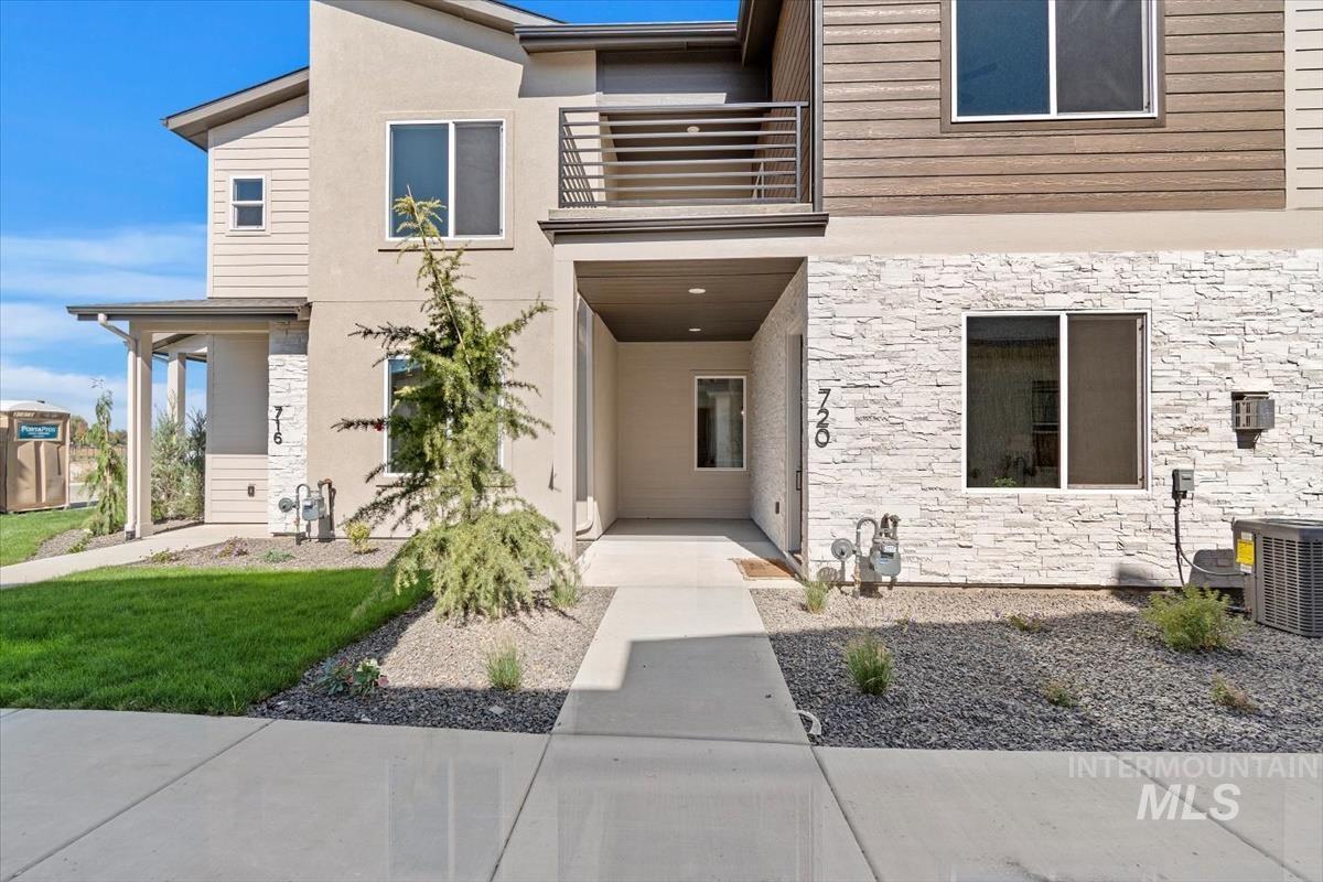 View of front of property with stone siding, a balcony, and stucco siding