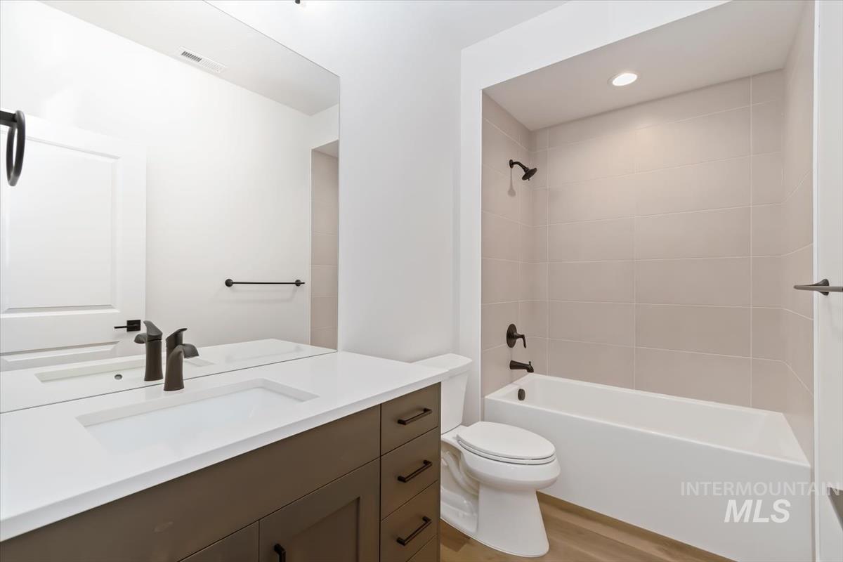 Bathroom featuring bathing tub / shower combination, vanity, and light wood-style flooring