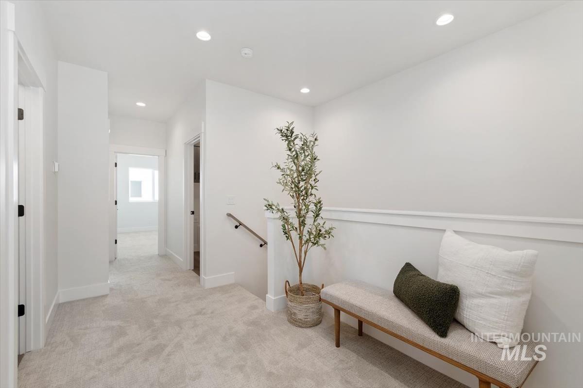Sitting room with an upstairs landing, light colored carpet, and recessed lighting