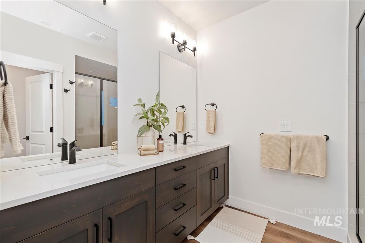 Bathroom with a stall shower, double vanity, and light wood-style flooring