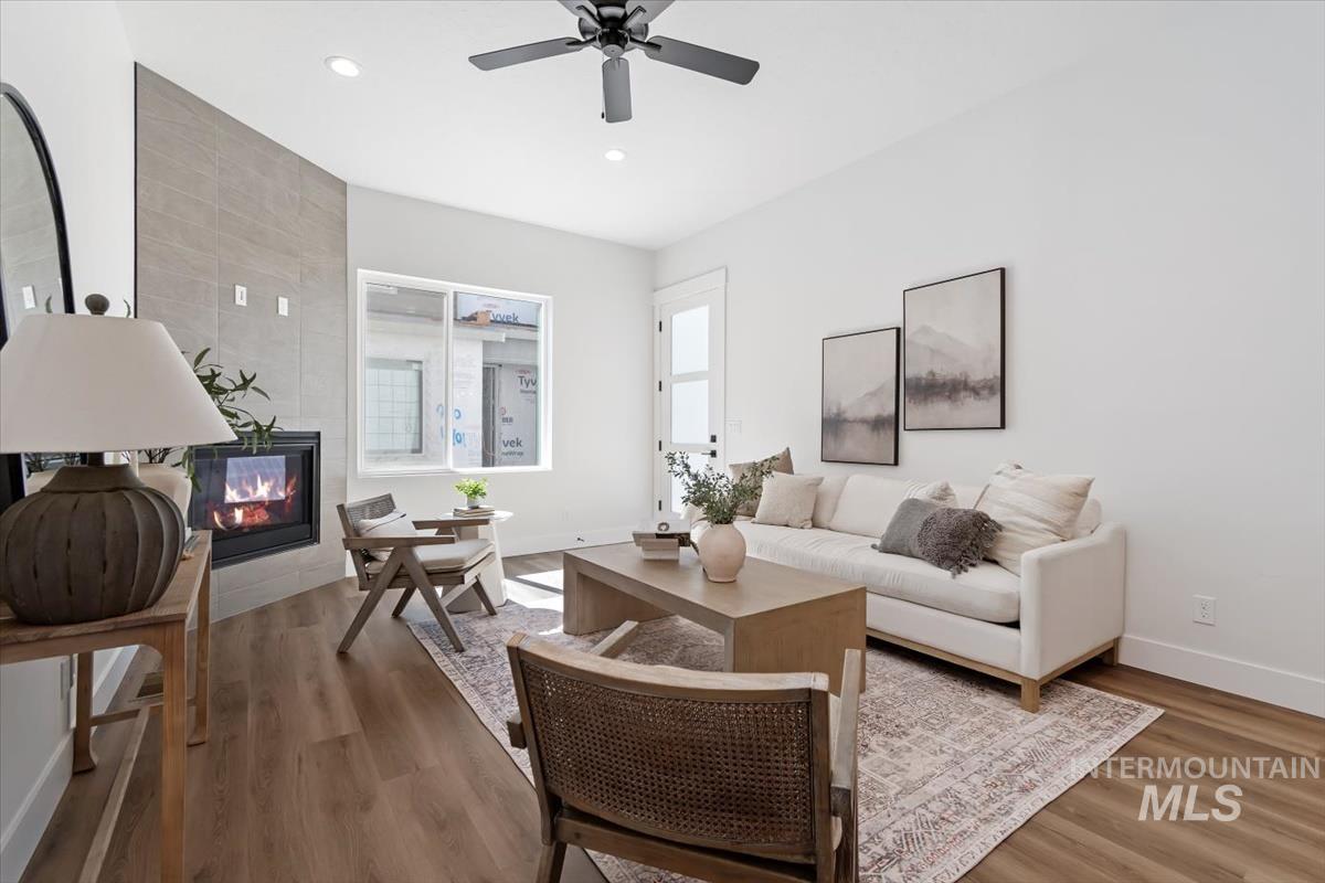Living room featuring wood finished floors, a tile fireplace, recessed lighting, and a ceiling fan