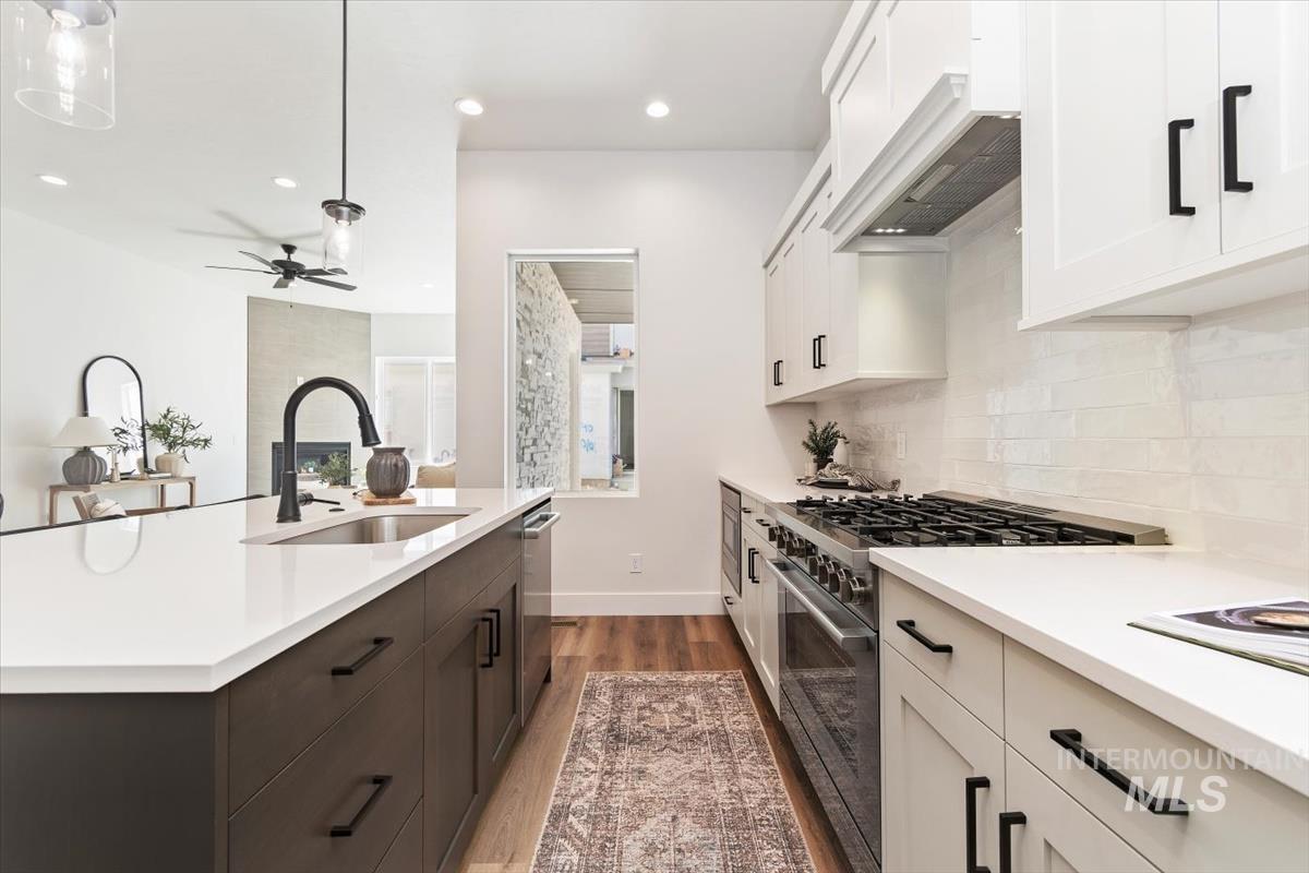 Kitchen with range with gas cooktop, white cabinetry, dark wood-type flooring, premium range hood, and recessed lighting