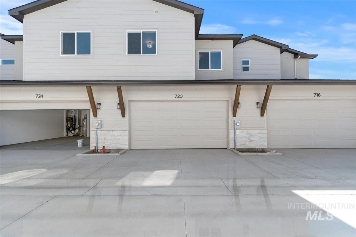 Rear view of property featuring driveway and stone siding