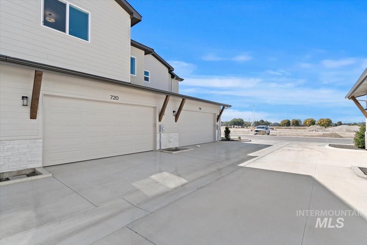 View of side of property with stone siding, concrete driveway, and an attached garage