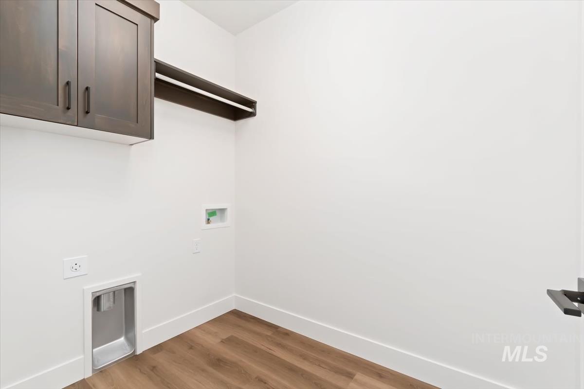 Washroom with wood finished floors, cabinet space, washer hookup, and hookup for an electric dryer