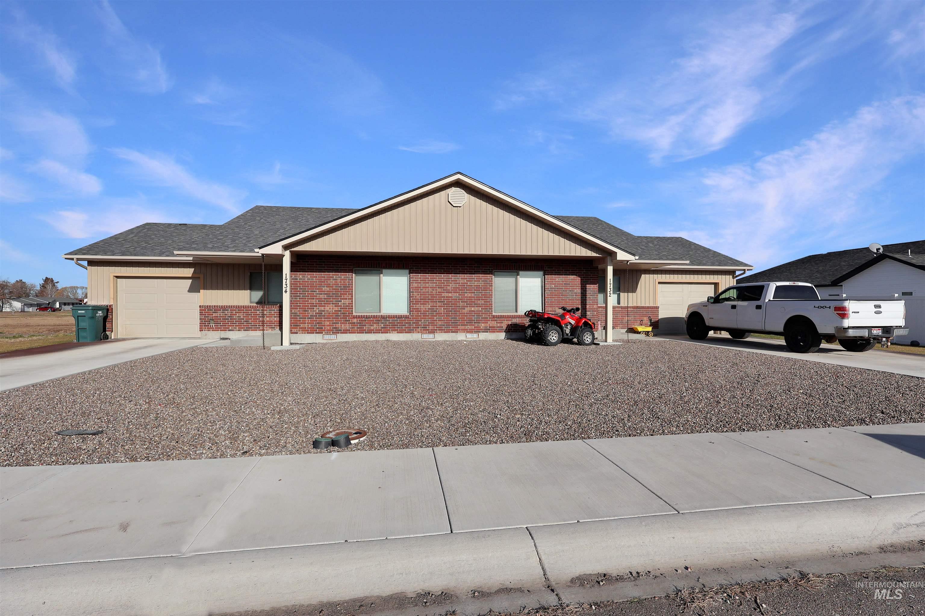 Single story home featuring brick siding, a garage, concrete driveway, and board and batten siding