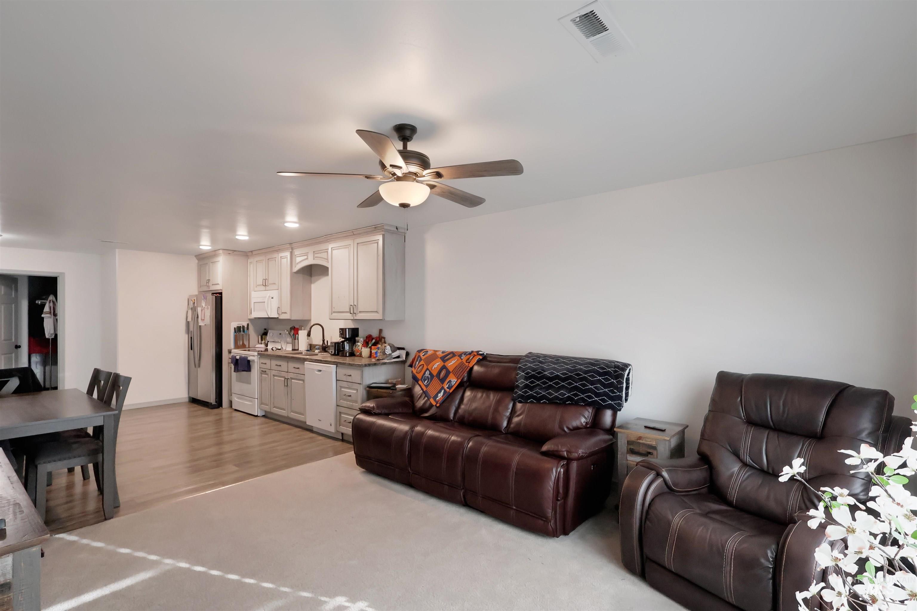 Living room featuring ceiling fan, light wood-style flooring, and light carpet