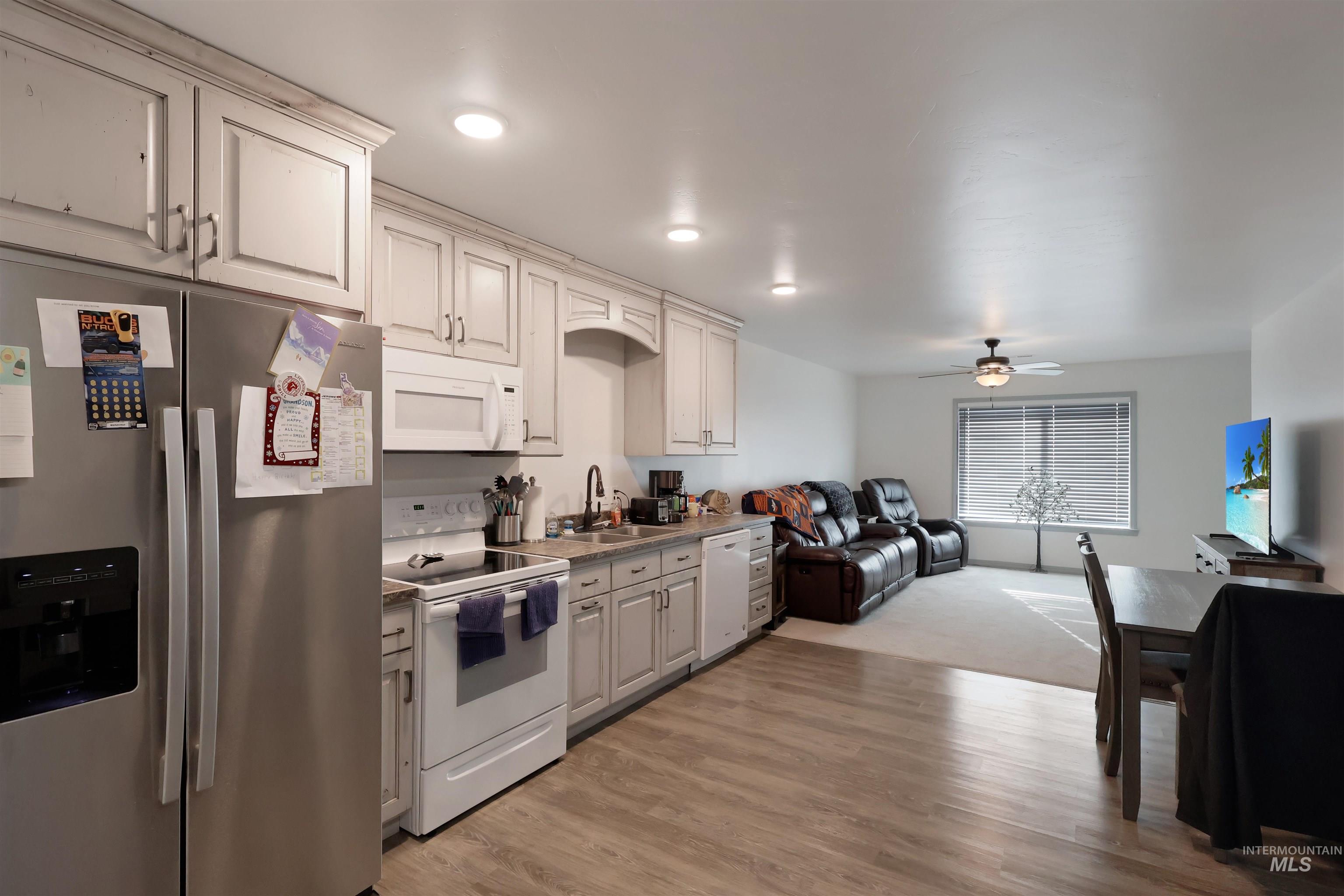 Kitchen featuring white appliances, open floor plan, light wood-style flooring, and ceiling fan