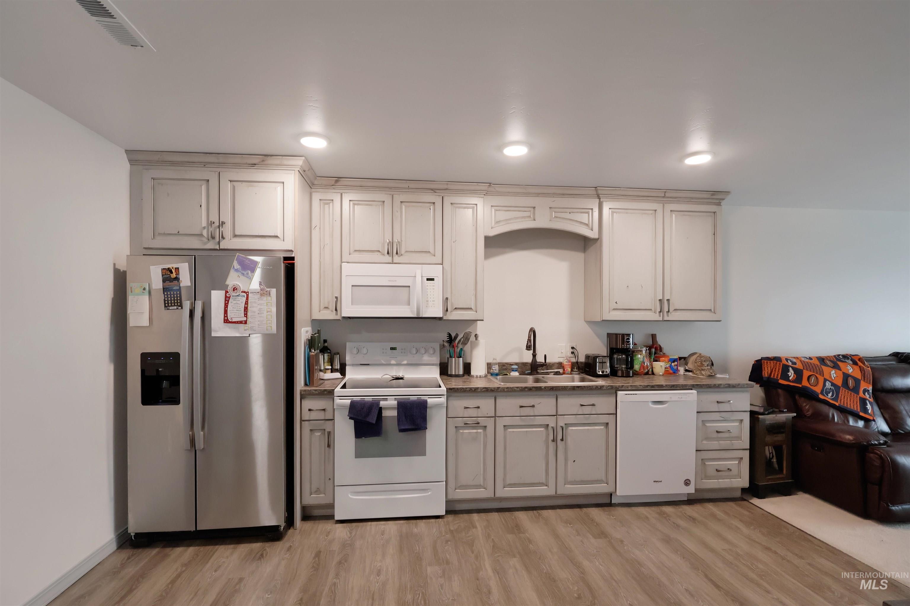 Kitchen with white appliances and light wood finished floors