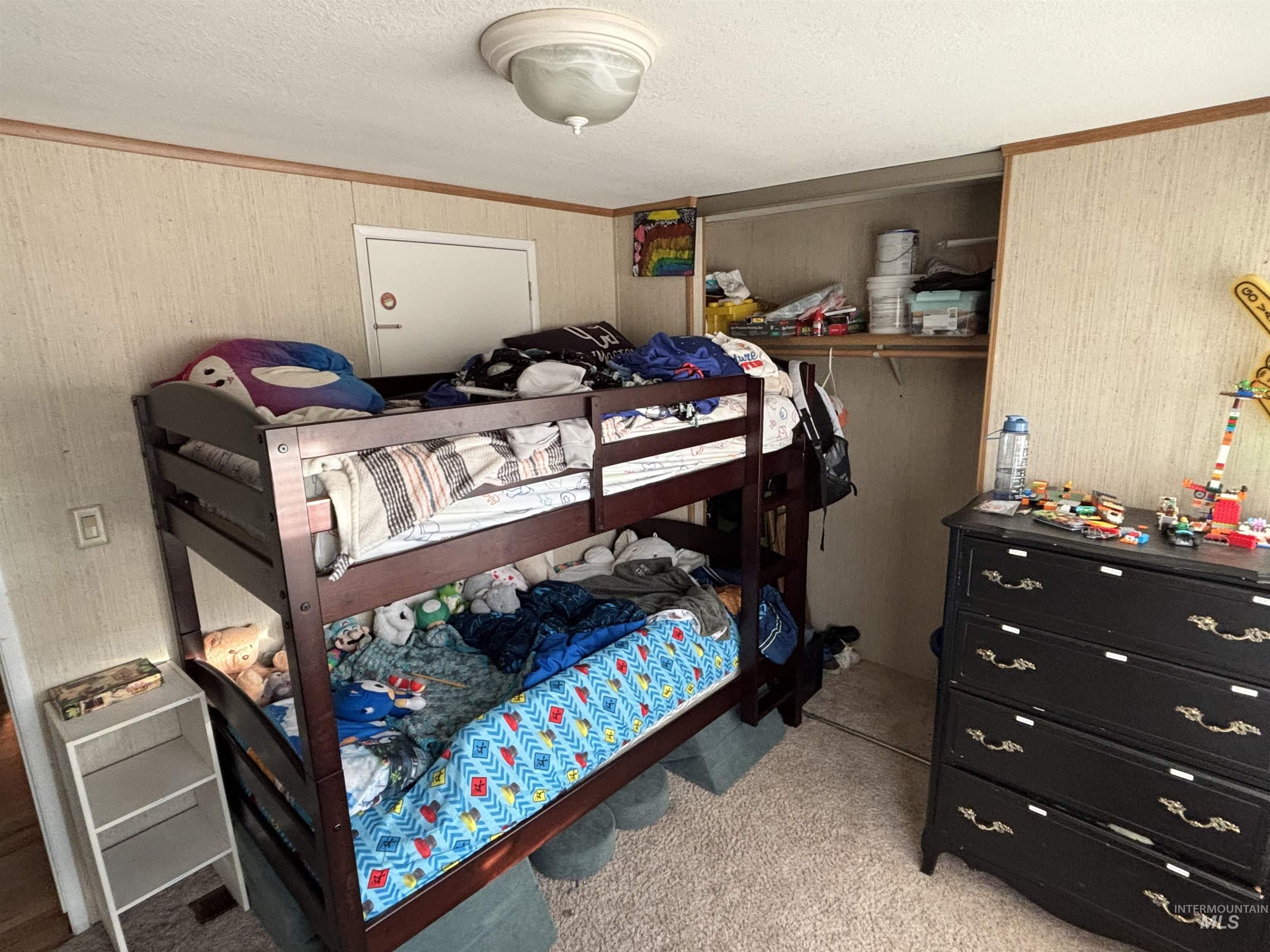 Bedroom featuring light carpet, a textured ceiling, and ornamental molding