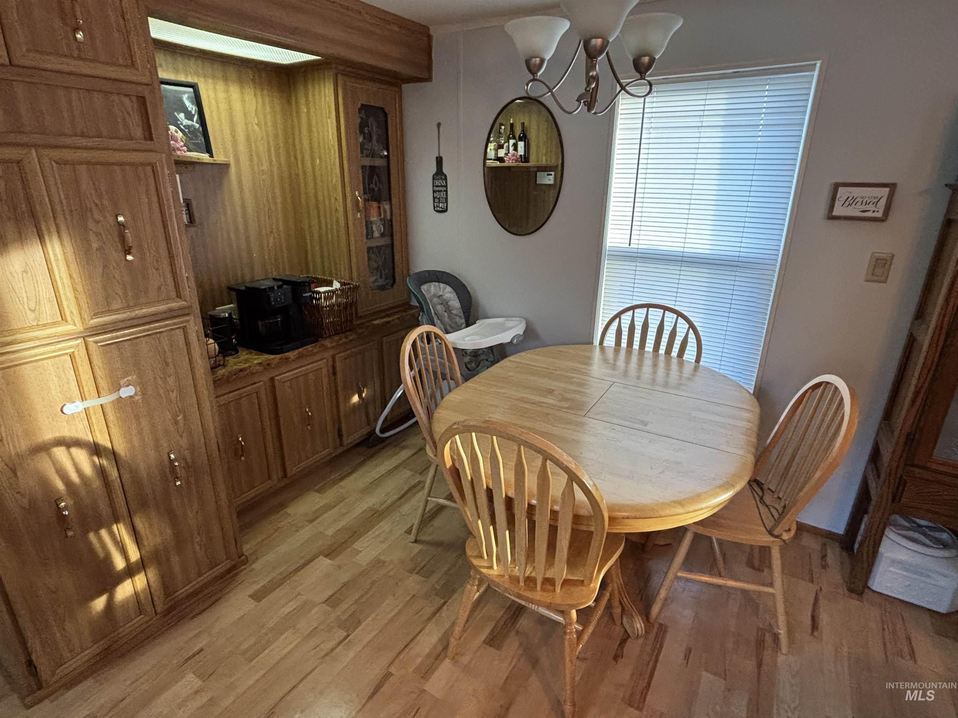Dining room with a chandelier, light wood-style floors, and wood walls