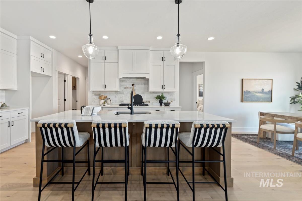 Kitchen with white cabinetry, a kitchen bar, hanging light fixtures, and recessed lighting