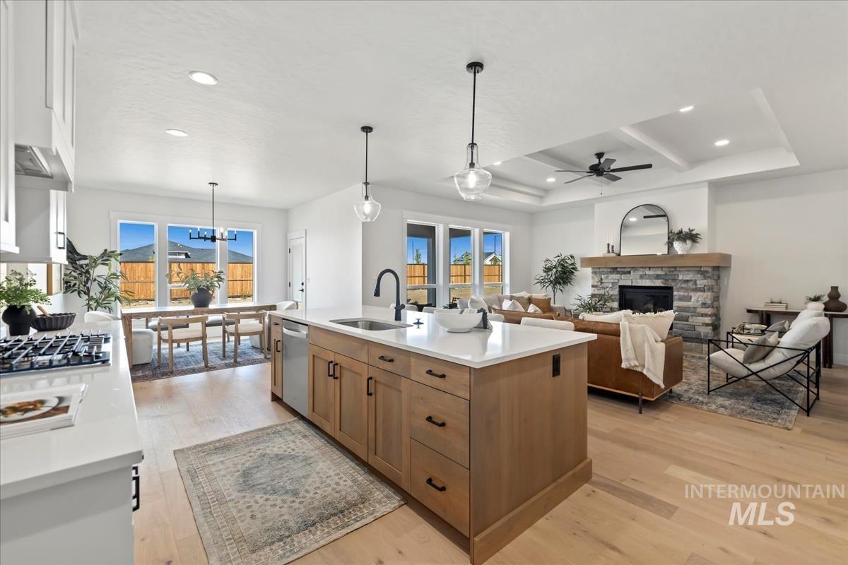 Kitchen with decorative light fixtures, light wood finished floors, a fireplace, open floor plan, and a ceiling fan