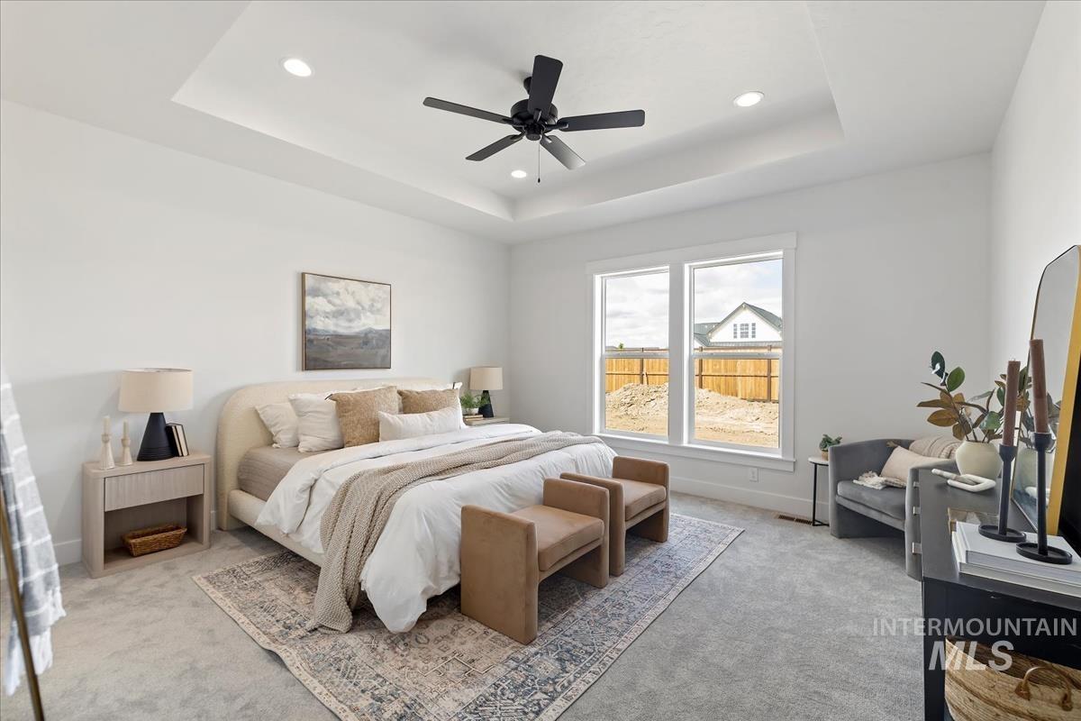 Bedroom with light carpet, ceiling fan, a raised ceiling, and recessed lighting