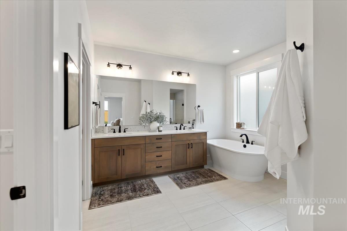 Bathroom featuring a soaking tub, double vanity, and light tile patterned flooring