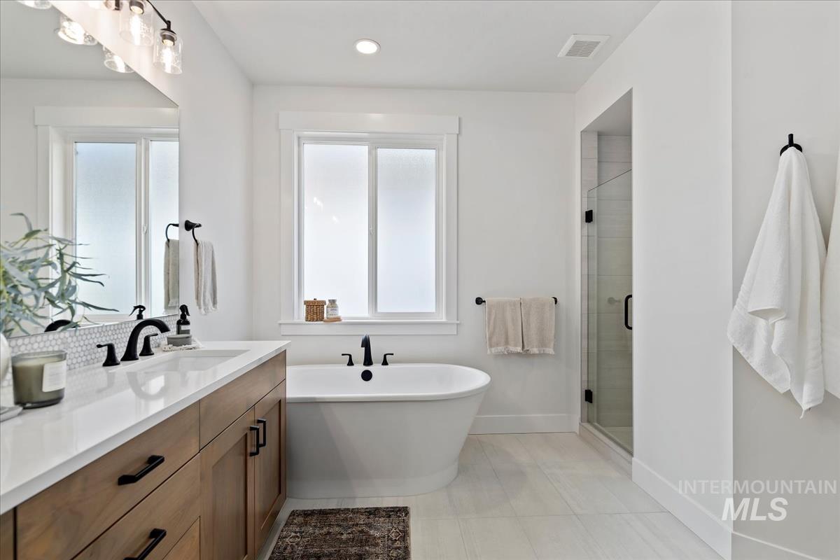 Bathroom with vanity, a soaking tub, a stall shower, light tile patterned flooring, and recessed lighting