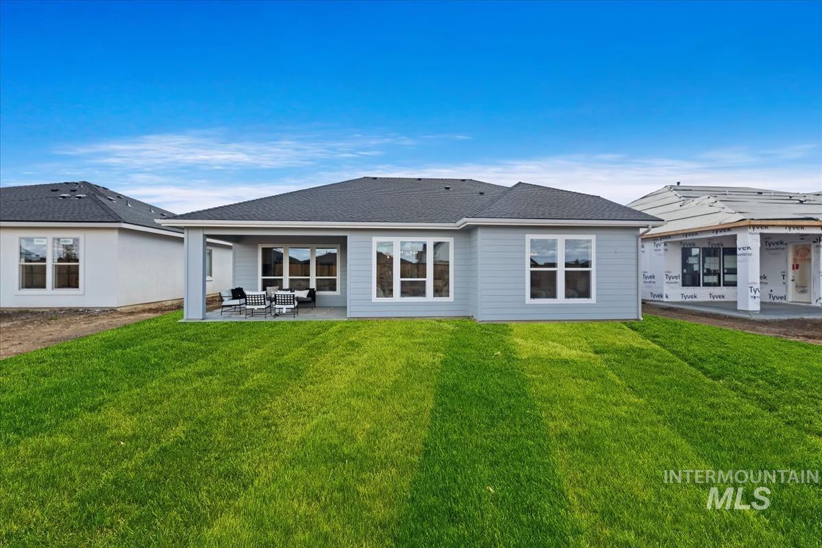 Rear view of house with a patio, a yard, and a shingled roof