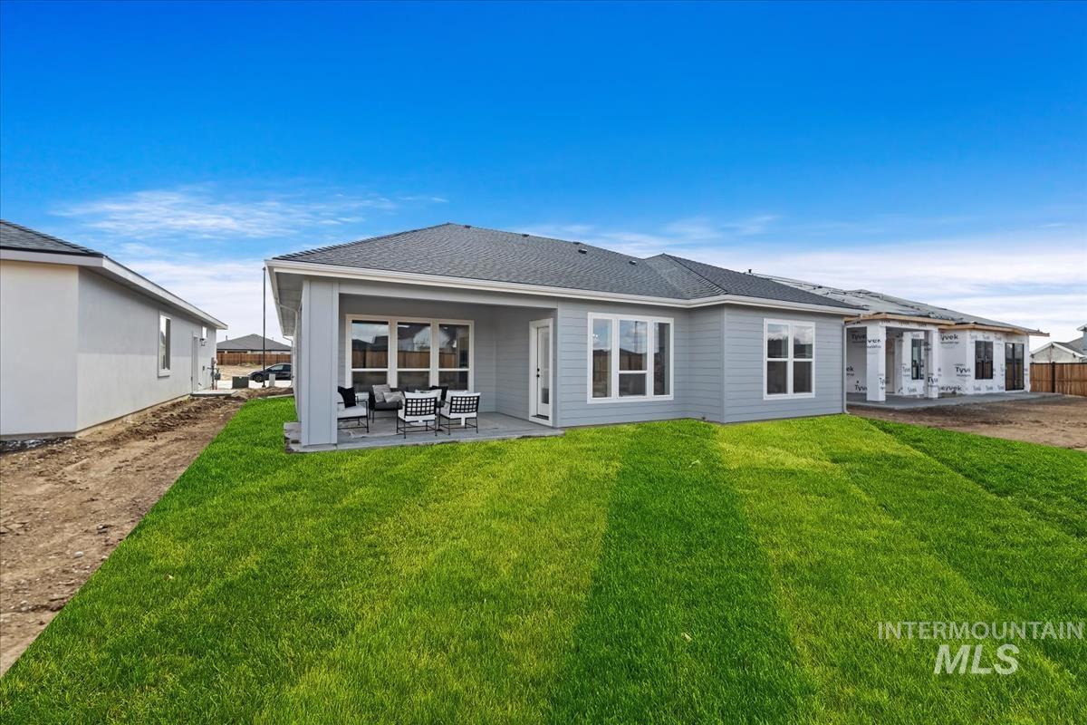 Back of property with a patio, a yard, and roof with shingles