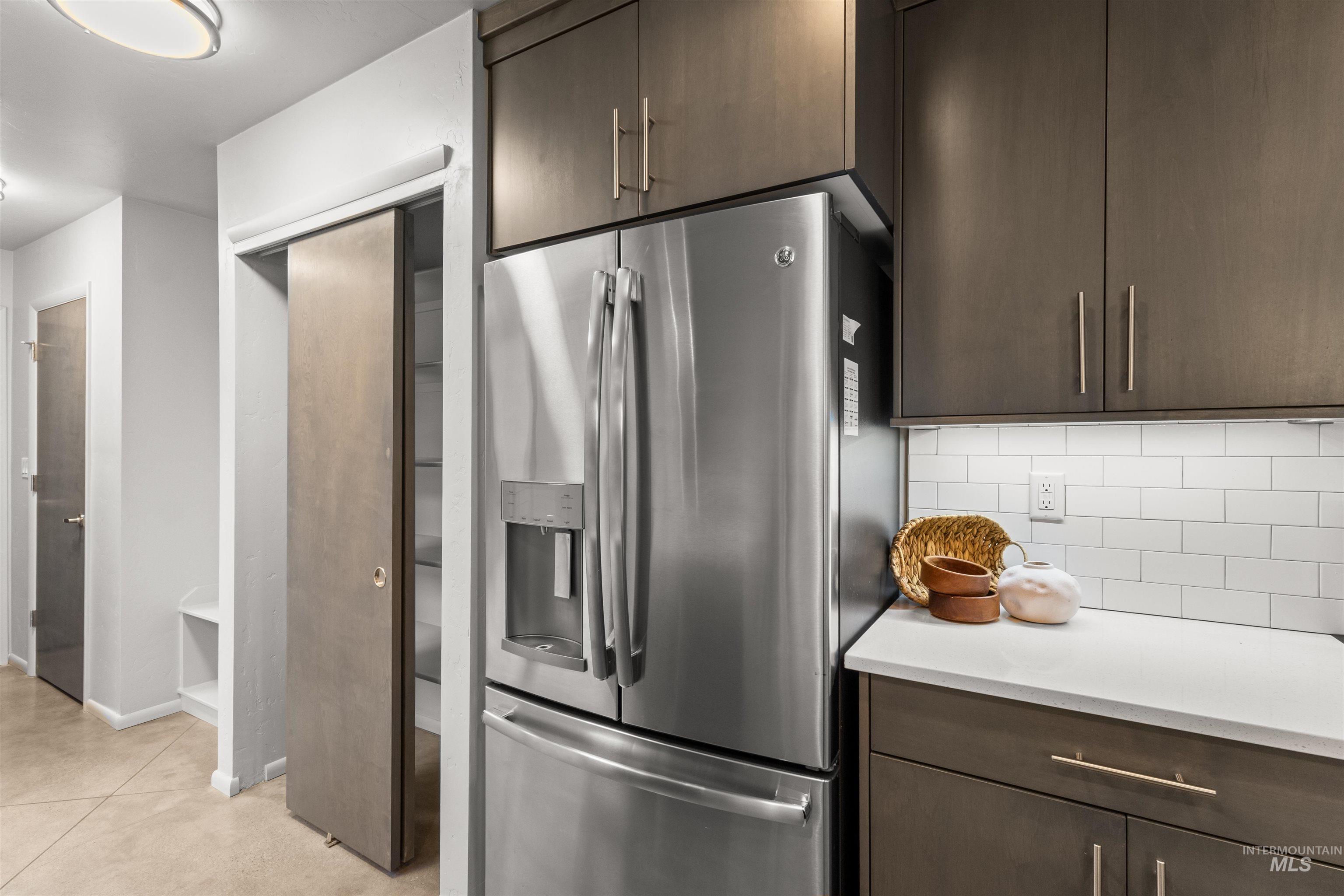 Kitchen featuring stainless steel fridge with ice dispenser, dark grey cabinetry, subway tile backsplash, and light quartz countertops