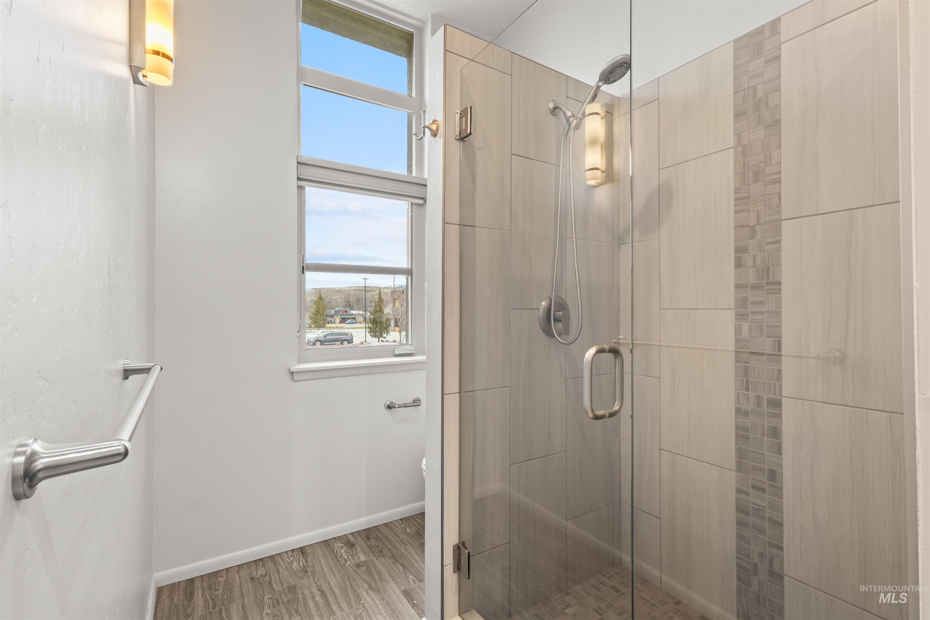 Full master bathroom featuring a shower stall and light wood-look tile plank floors