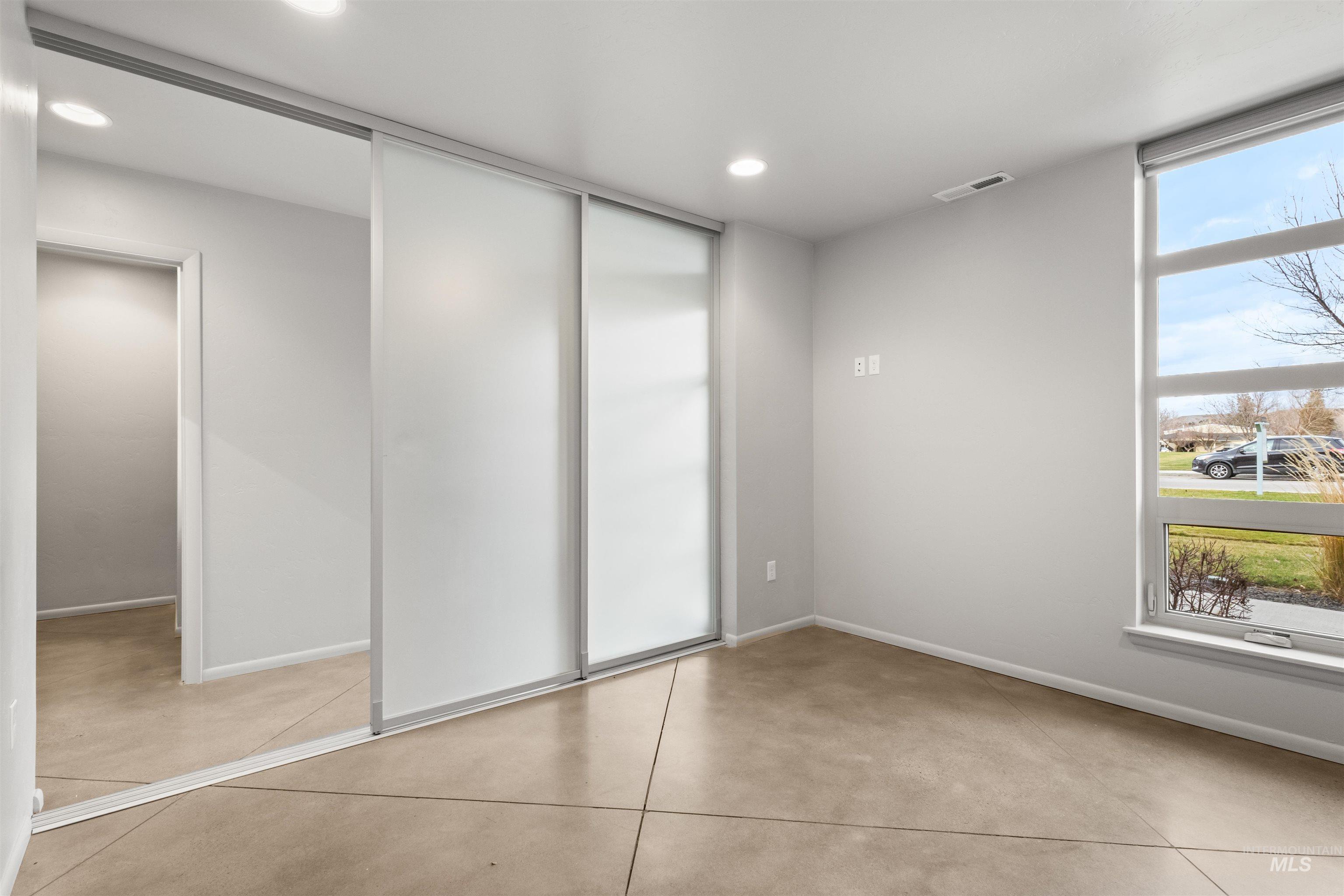 bedroom/flex room with multiple windows, recessed lighting, concrete floors, and a closet